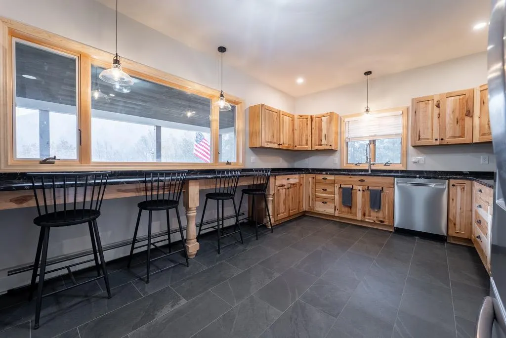 Kitchen featuring a kitchen breakfast bar, light brown cabinetry, dishwasher, and decorative light fixtures Kitchen featuring a kitchen breakfast bar, light brown cabinetry, dishwasher, and decorative light fixtures