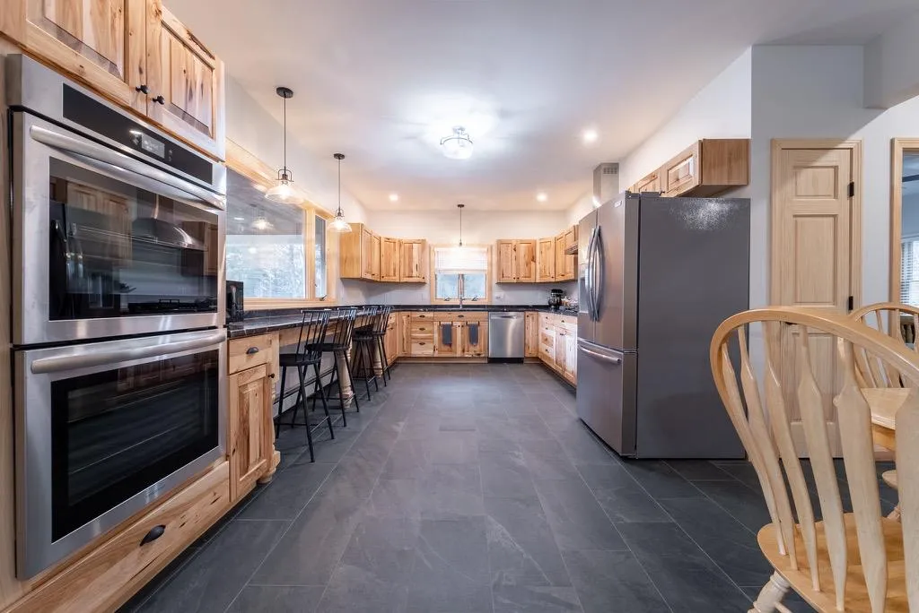 Kitchen featuring light brown cabinetry, pendant lighting, and stainless steel appliances Kitchen featuring light brown cabinetry, pendant lighting, and stainless steel appliances