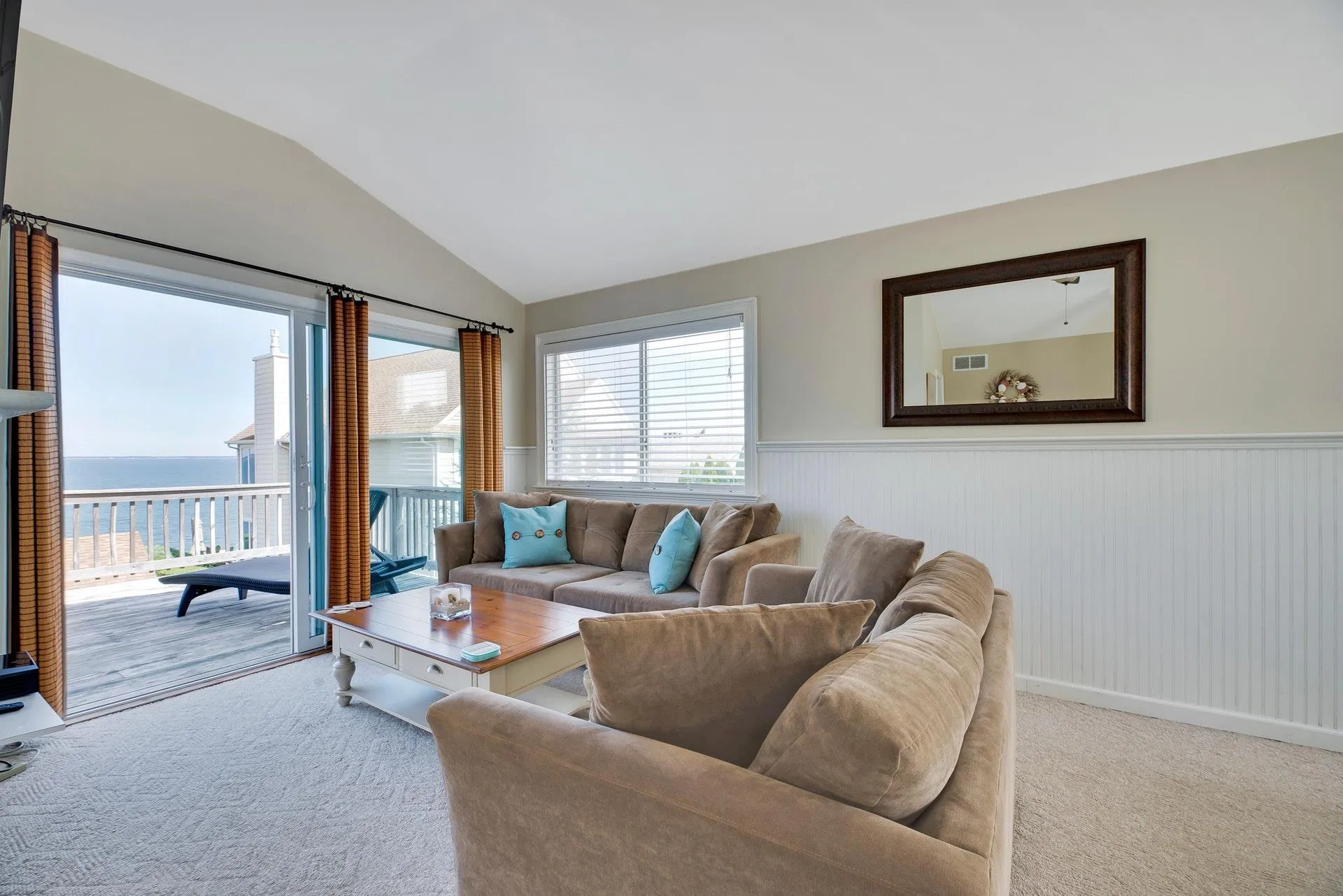 Carpeted living room featuring a water view and vaulted ceiling Carpeted living room featuring a water view and vaulted ceiling