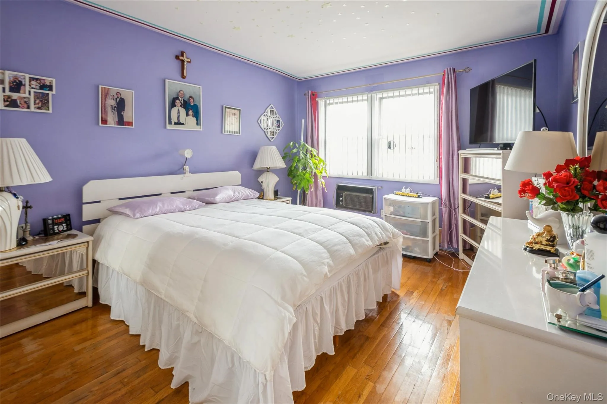 Bedroom featuring wood flooring and a wall unit AC Bedroom featuring wood flooring and a wall unit AC