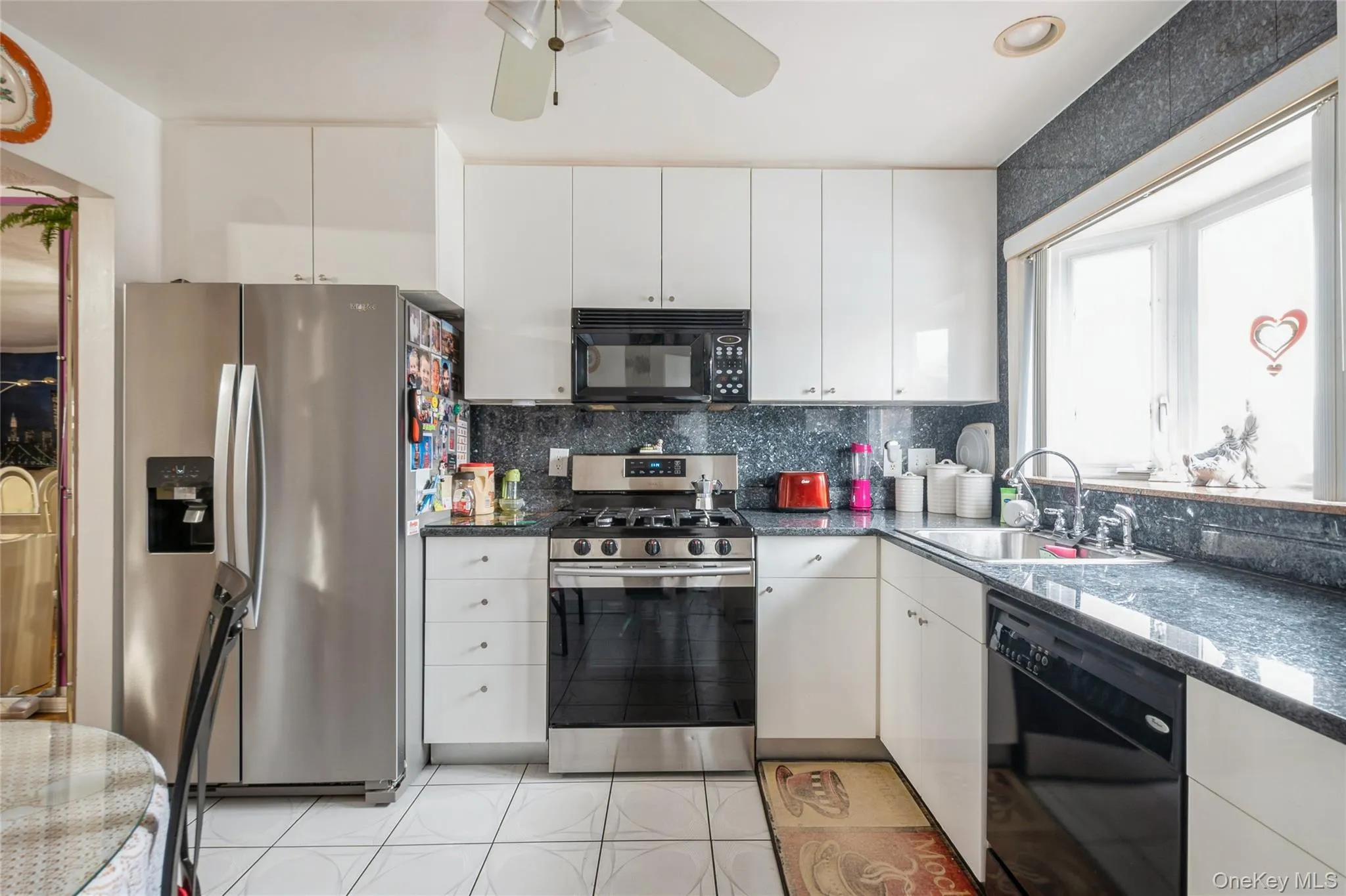 Kitchen featuring white cabinets, young appliances and granite counters & tasteful backsplash Kitchen featuring white cabinets, young appliances and granite counters & tasteful backsplash