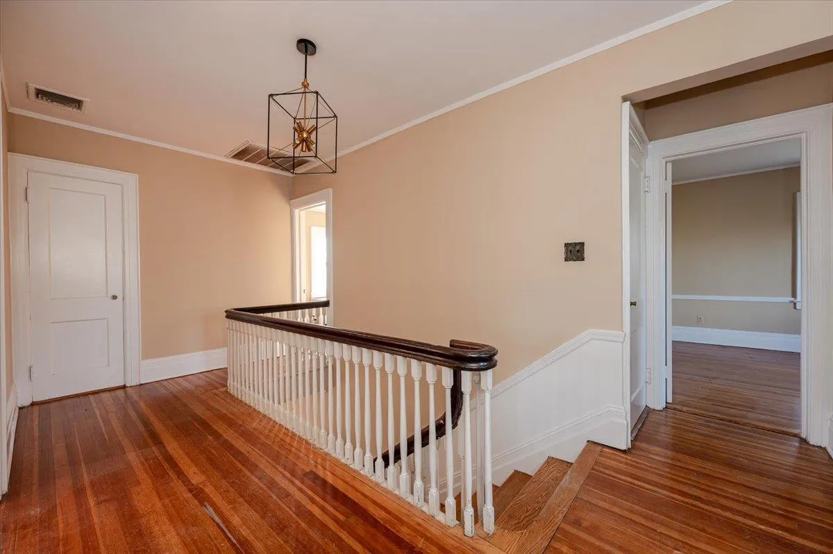 Corridor with dark hardwood / wood-style flooring, crown molding, and a chandelier Corridor with dark hardwood / wood-style flooring, crown molding, and a chandelier