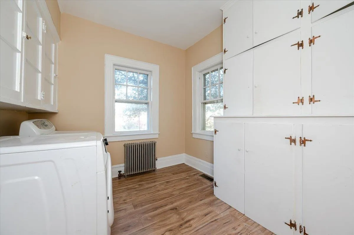 Washroom featuring cabinets, light hardwood / wood-style floors, radiator, and washing machine and clothes dryer Washroom featuring cabinets, light hardwood / wood-style floors, radiator, and washing machine and clothes dryer