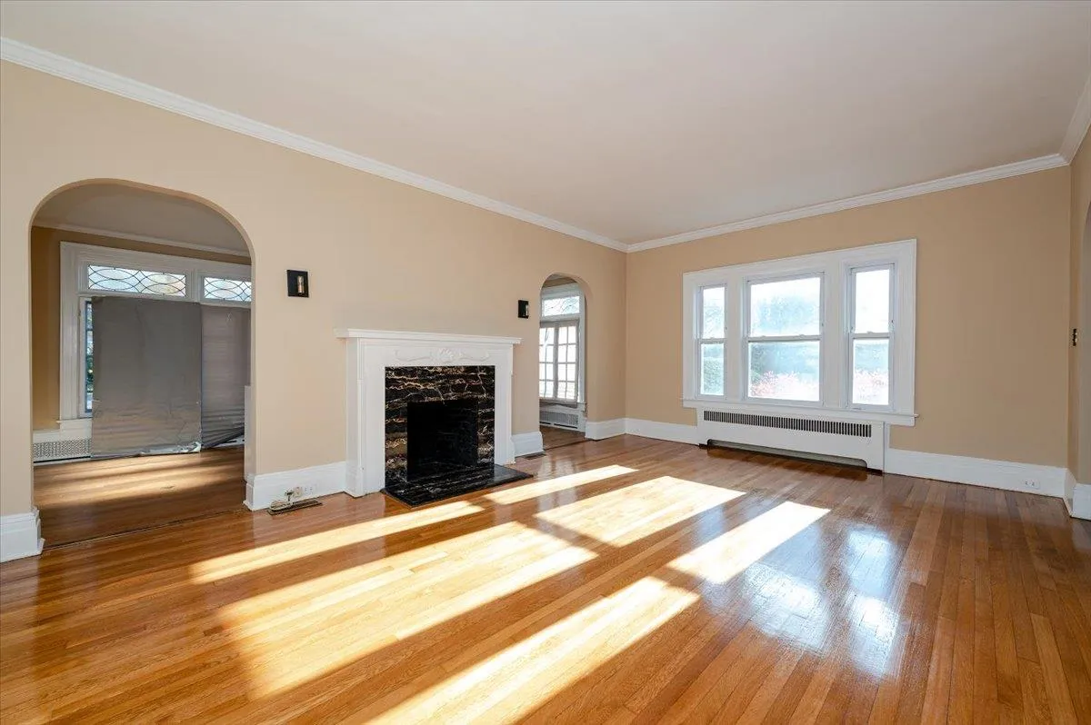 Unfurnished living room featuring hardwood / wood-style floors, radiator heating unit, ornamental molding, and a fireplace Unfurnished living room featuring hardwood / wood-style floors, radiator heating unit, ornamental molding, and a fireplace