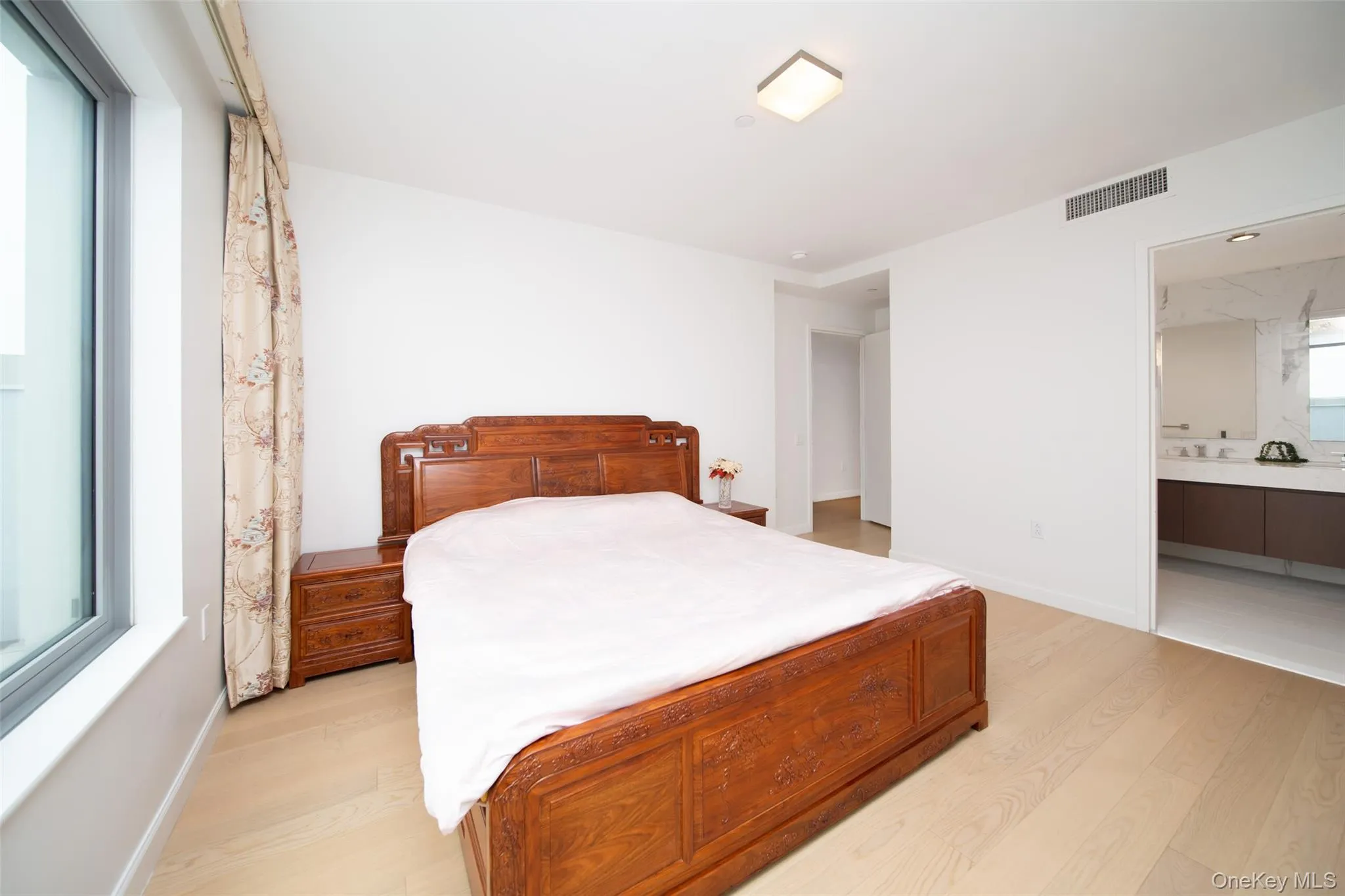 Bedroom featuring multiple windows, light hardwood / wood-style flooring, and ensuite bath Bedroom featuring multiple windows, light hardwood / wood-style flooring, and ensuite bath