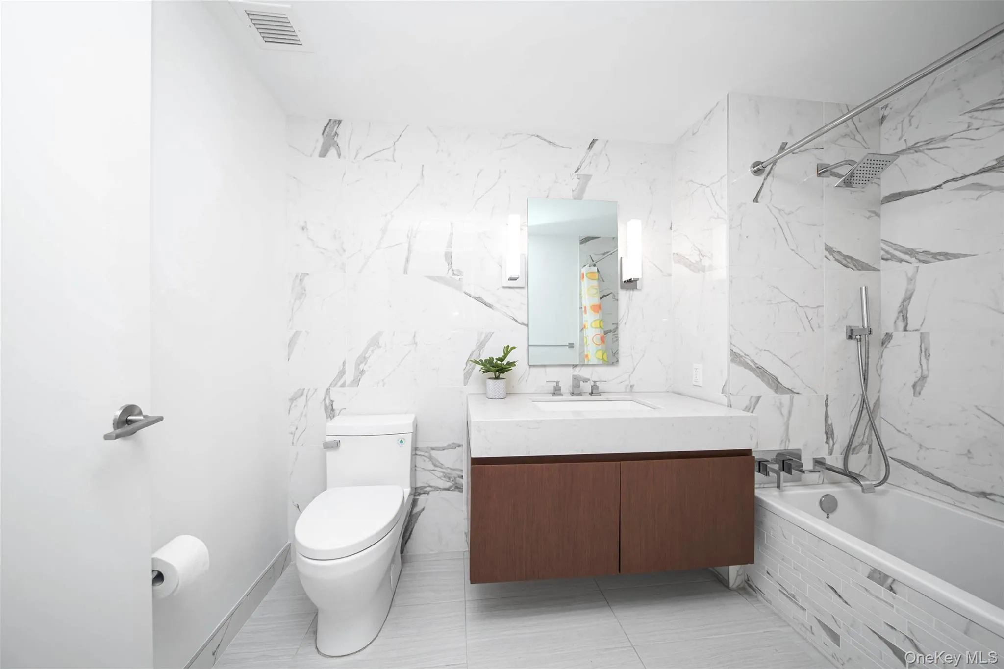 Full bathroom with tile walls, toilet, vanity, and tiled shower / bath Full bathroom with tile walls, toilet, vanity, and tiled shower / bath
