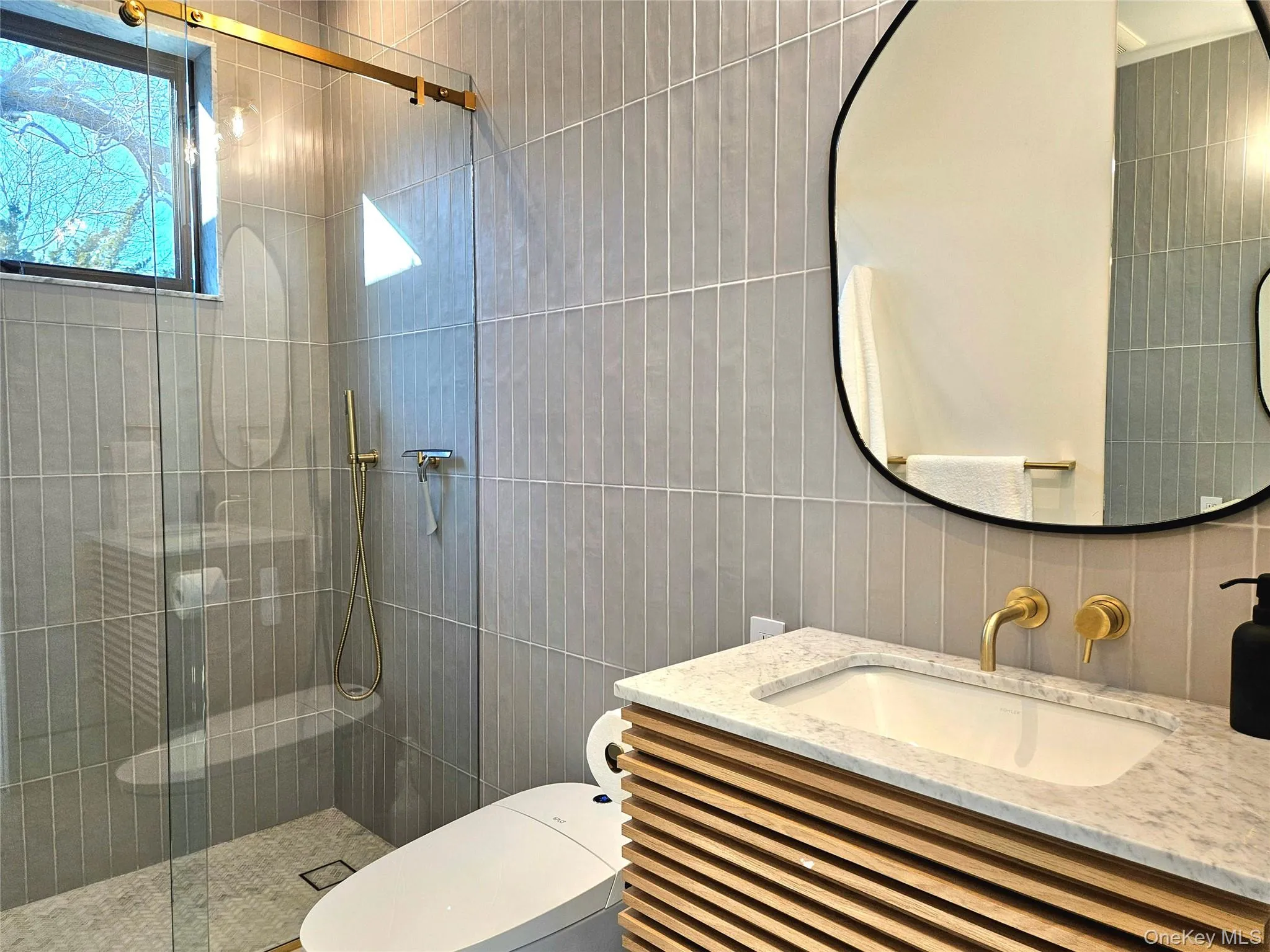 Bathroom with tile walls, a shower stall, toilet, vanity, and tasteful backsplash Bathroom with tile walls, a shower stall, toilet, vanity, and tasteful backsplash