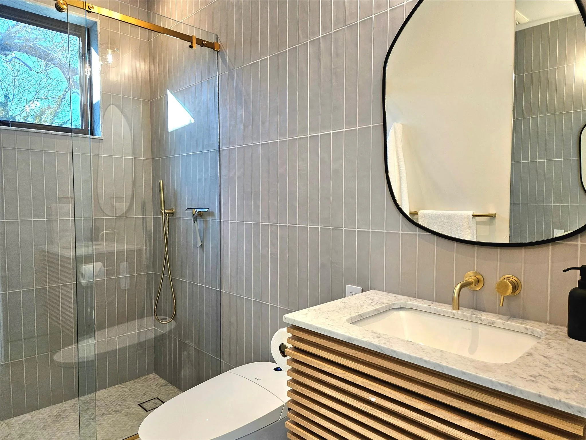 Bathroom with tile walls, a shower stall, toilet, vanity, and tasteful backsplash Bathroom with tile walls, a shower stall, toilet, vanity, and tasteful backsplash