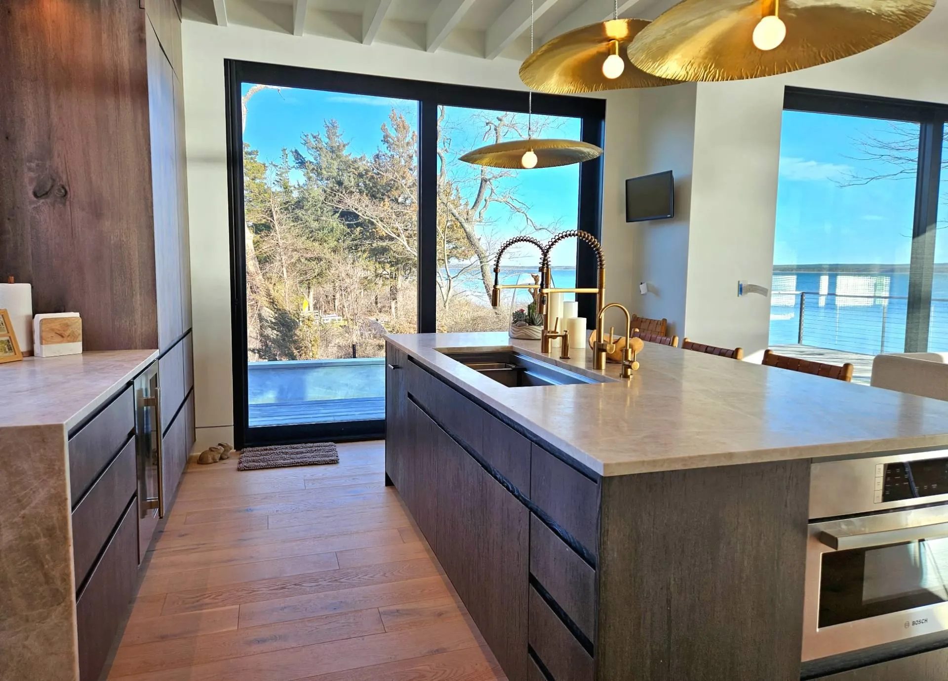 Kitchen featuring a center island with sink, light countertops, light wood-type flooring, stainless steel oven, and a sink Kitchen featuring a center island with sink, light countertops, light wood-type flooring, stainless steel oven, and a sink