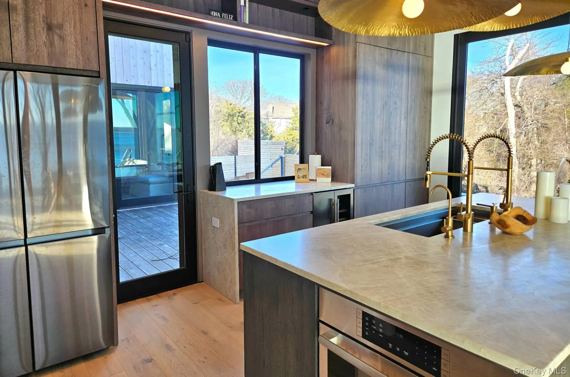 Kitchen featuring wine cooler, stainless steel refrigerator, light countertops, light wood-style floors, and a sink Kitchen featuring wine cooler, stainless steel refrigerator, light countertops, light wood-style floors, and a sink