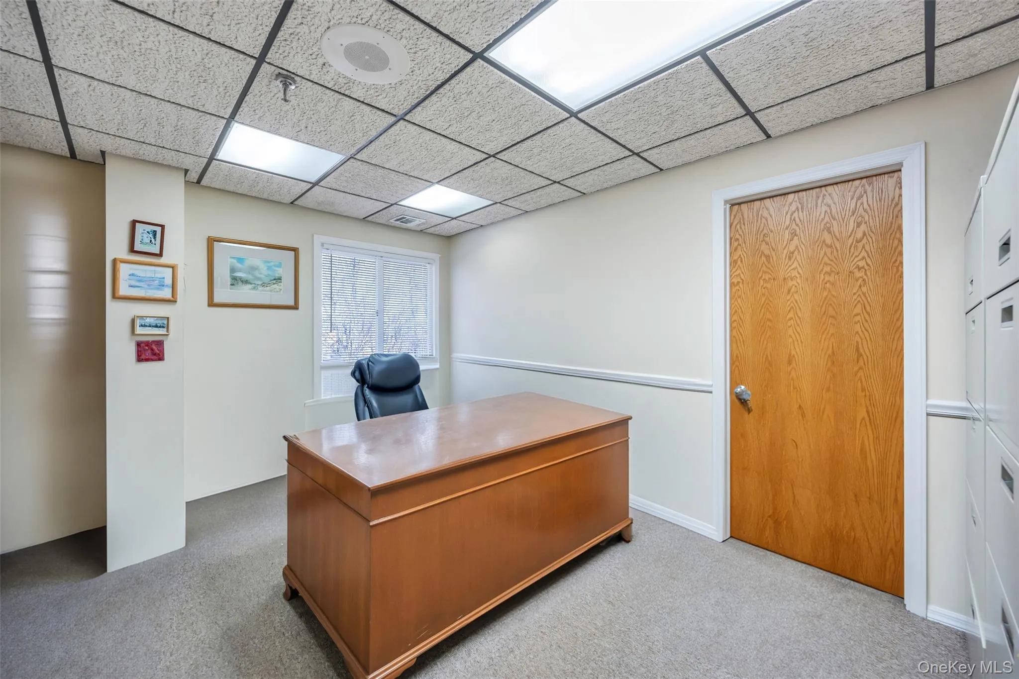 Home office with light colored carpet and a drop ceiling Home office with light colored carpet and a drop ceiling