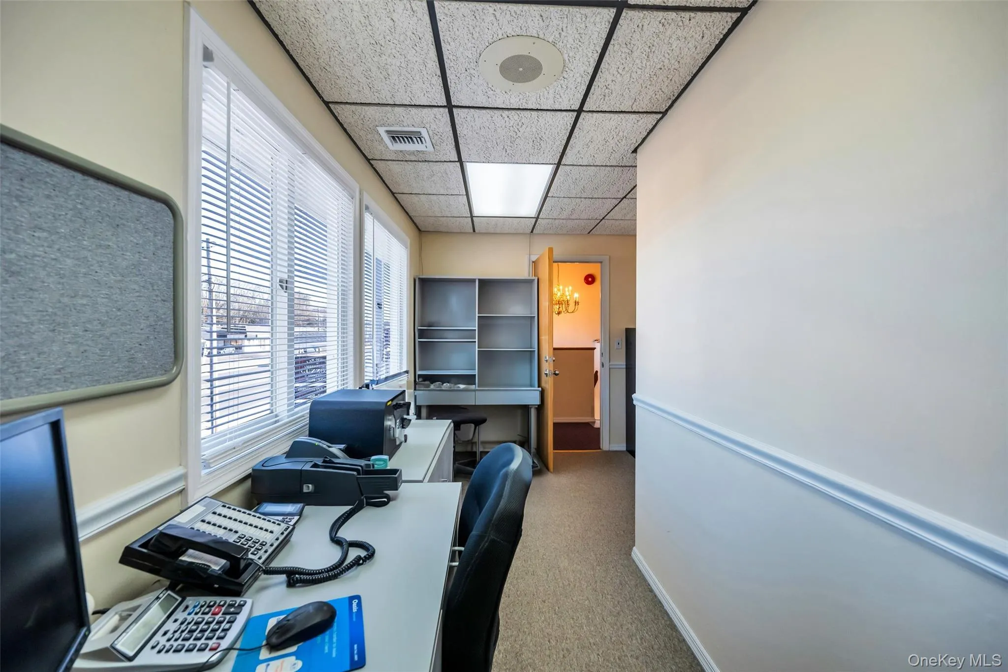 Office with a paneled ceiling and carpet flooring Office with a paneled ceiling and carpet flooring