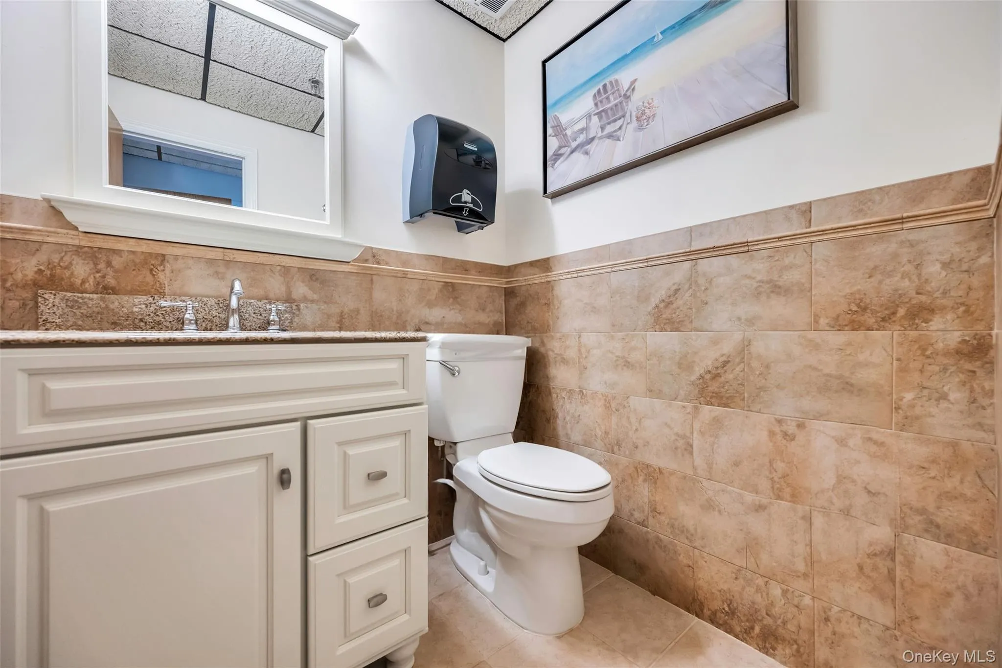 Bathroom with tile walls, tile patterned flooring, vanity, and toilet Bathroom with tile walls, tile patterned flooring, vanity, and toilet