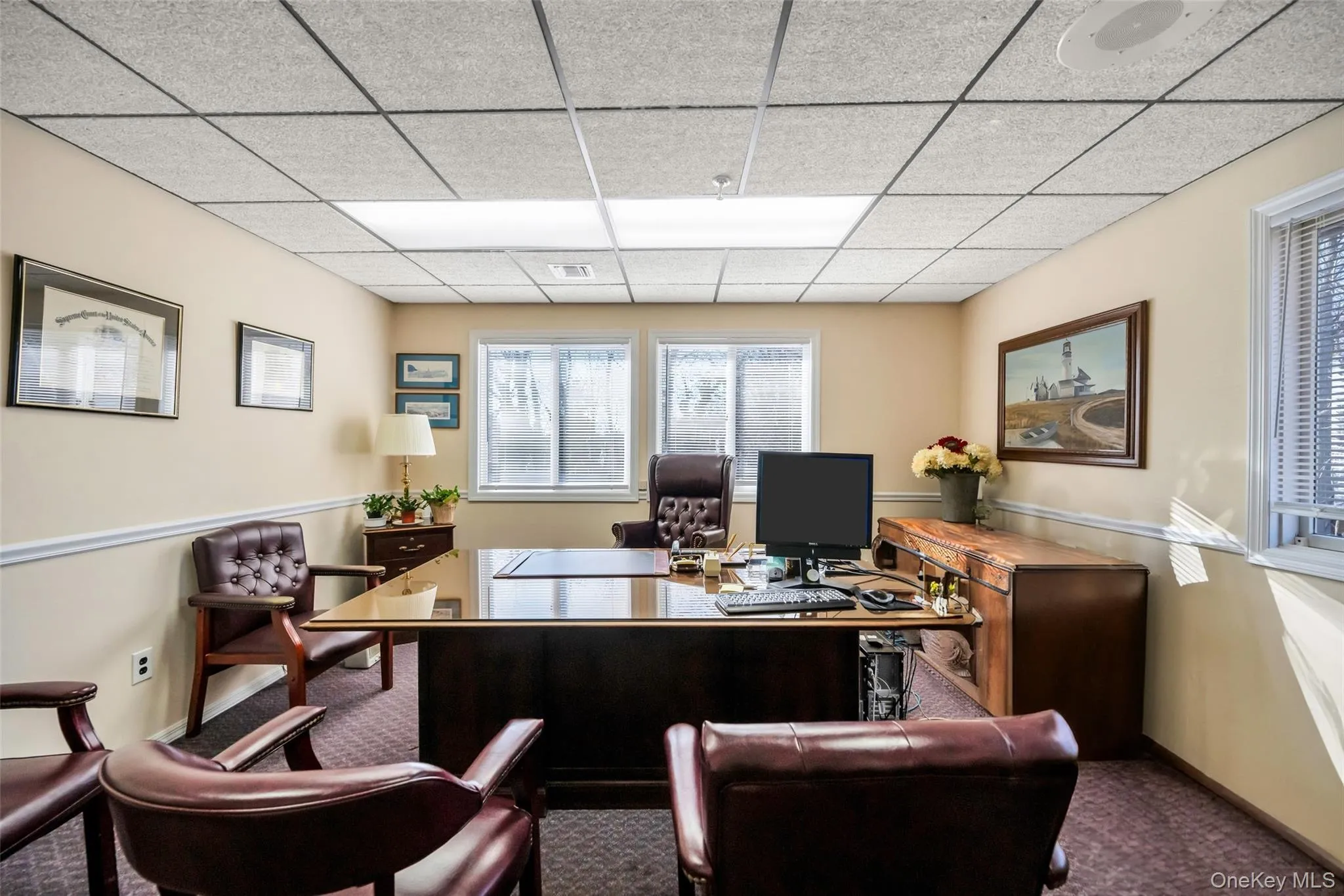 Office space with a paneled ceiling and carpet floors Office space with a paneled ceiling and carpet floors