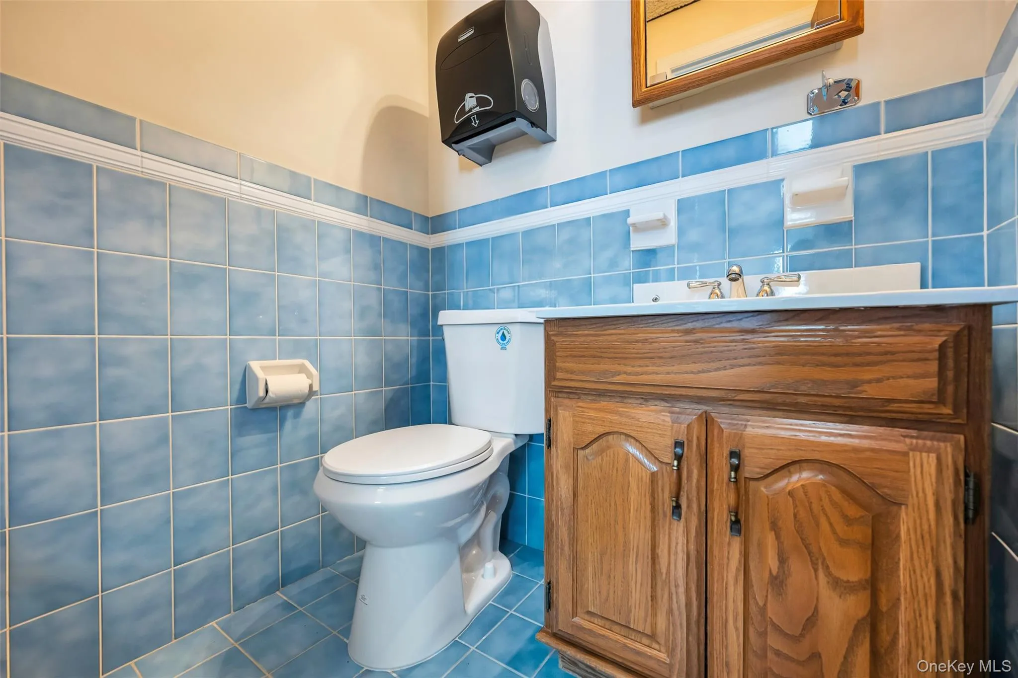 Bathroom featuring toilet, tile patterned flooring, tile walls, and vanity Bathroom featuring toilet, tile patterned flooring, tile walls, and vanity