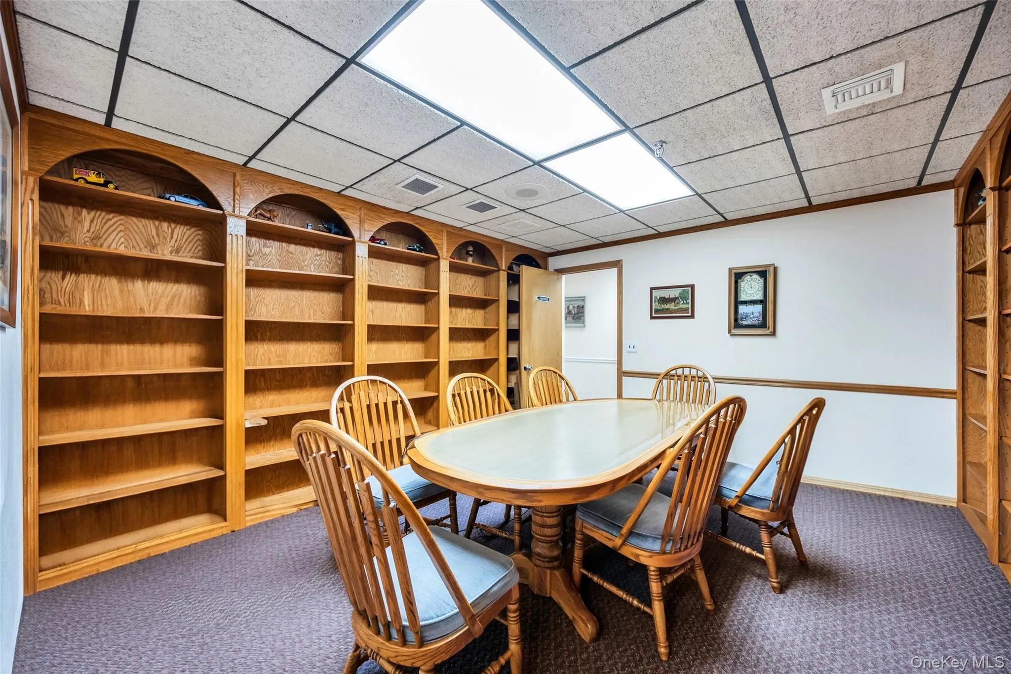 Dining room with a paneled ceiling, built in shelves, and carpet flooring Dining room with a paneled ceiling, built in shelves, and carpet flooring
