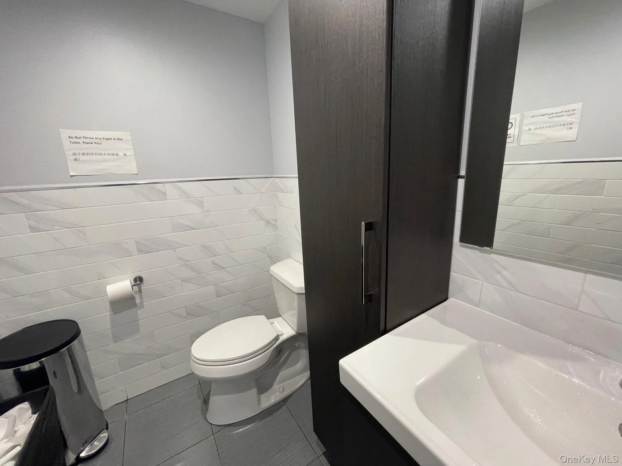 Bathroom featuring toilet, vanity, tile walls, and tile patterned floors Bathroom featuring toilet, vanity, tile walls, and tile patterned floors