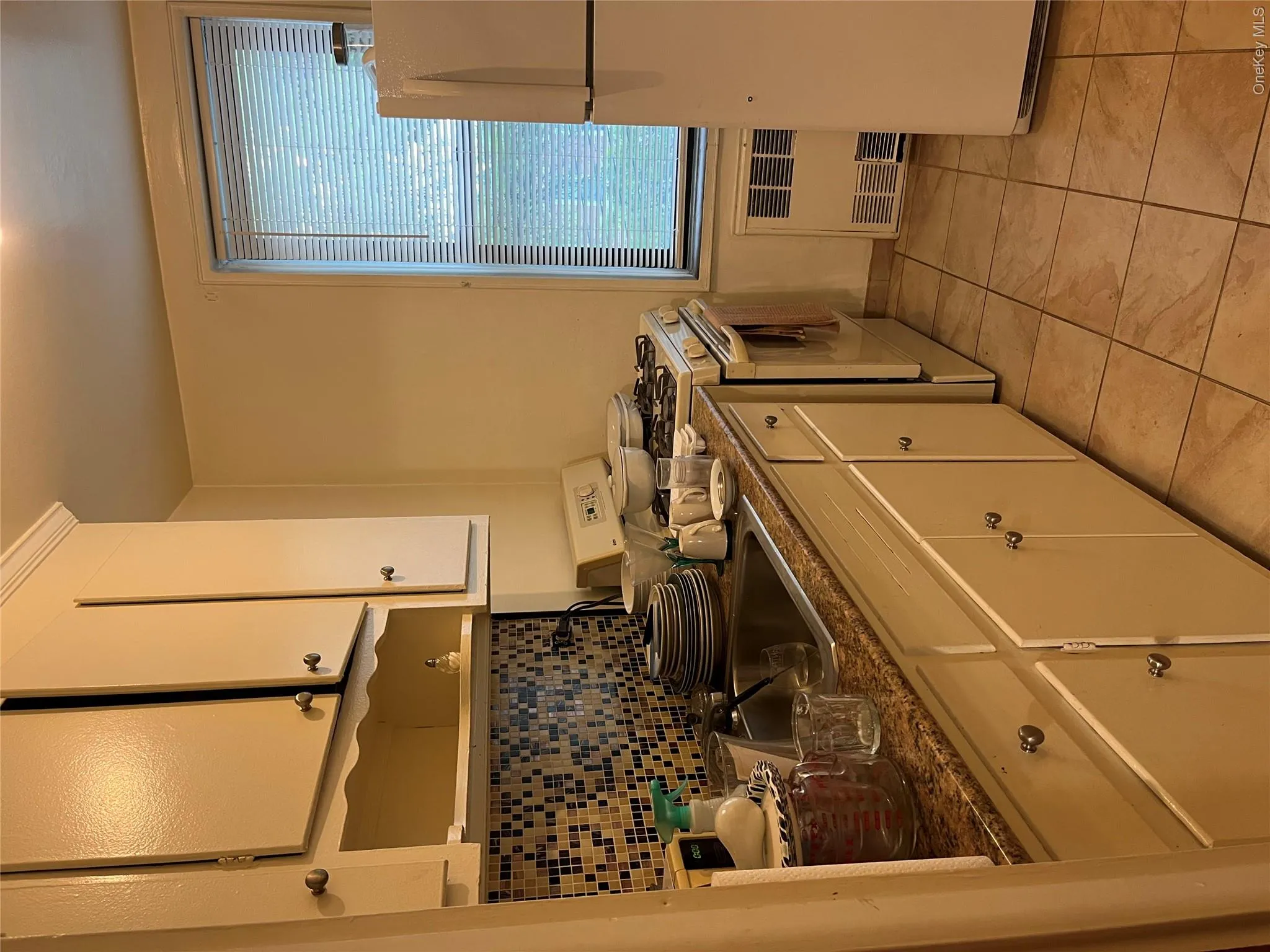 Kitchen with range, radiator heating unit, white cabinetry, fridge, and light tile patterned floors Kitchen with range, radiator heating unit, white cabinetry, fridge, and light tile patterned floors