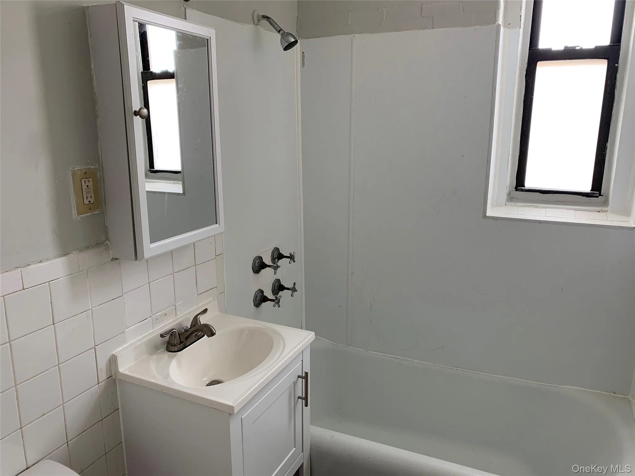 Full bathroom with vanity, shower / bath combination, tile walls, and decorative backsplash Full bathroom with vanity, shower / bath combination, tile walls, and decorative backsplash