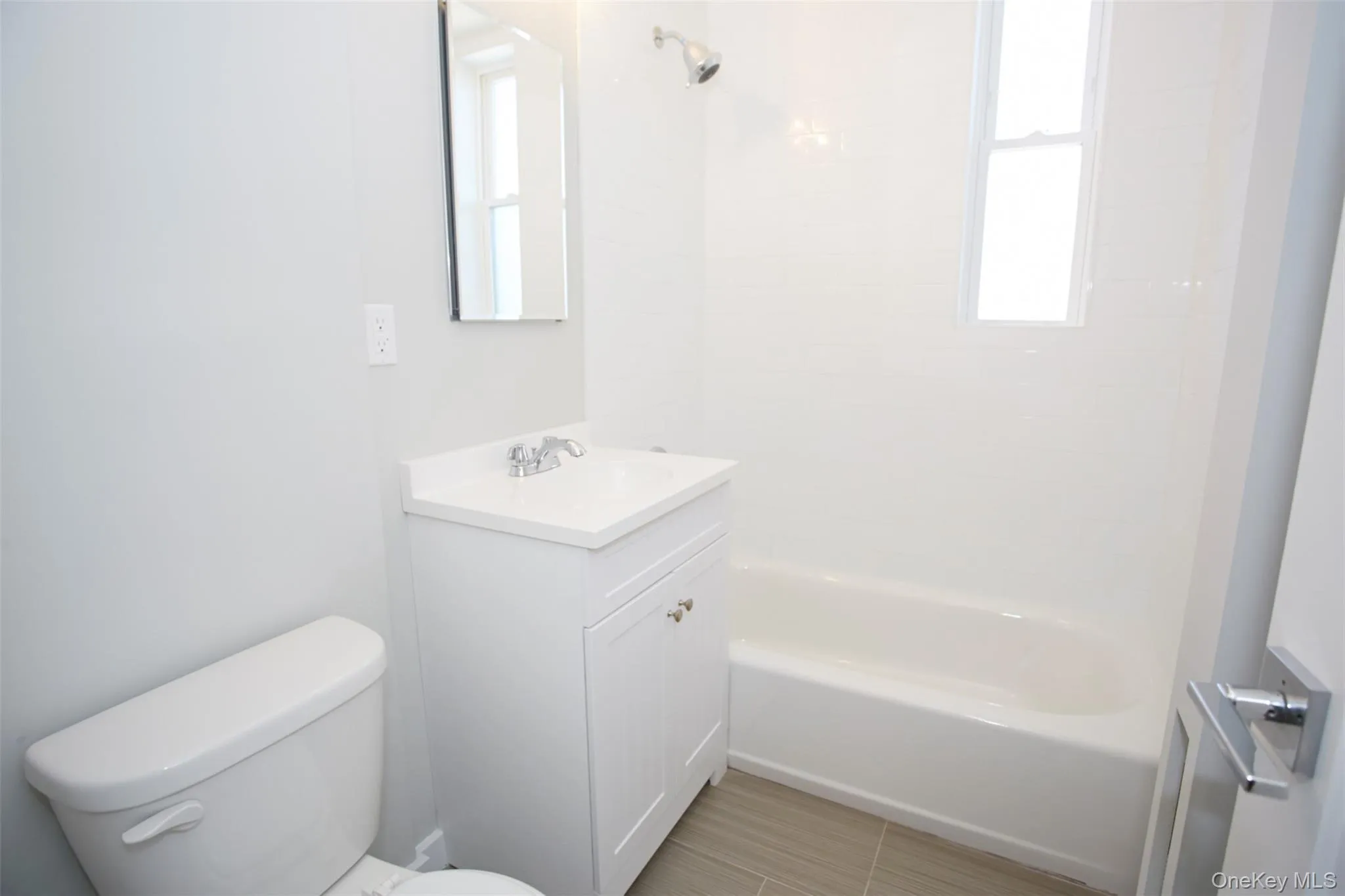 Bathroom featuring healthy amount of natural light, vanity, and bathtub / shower combination Bathroom featuring healthy amount of natural light, vanity, and bathtub / shower combination