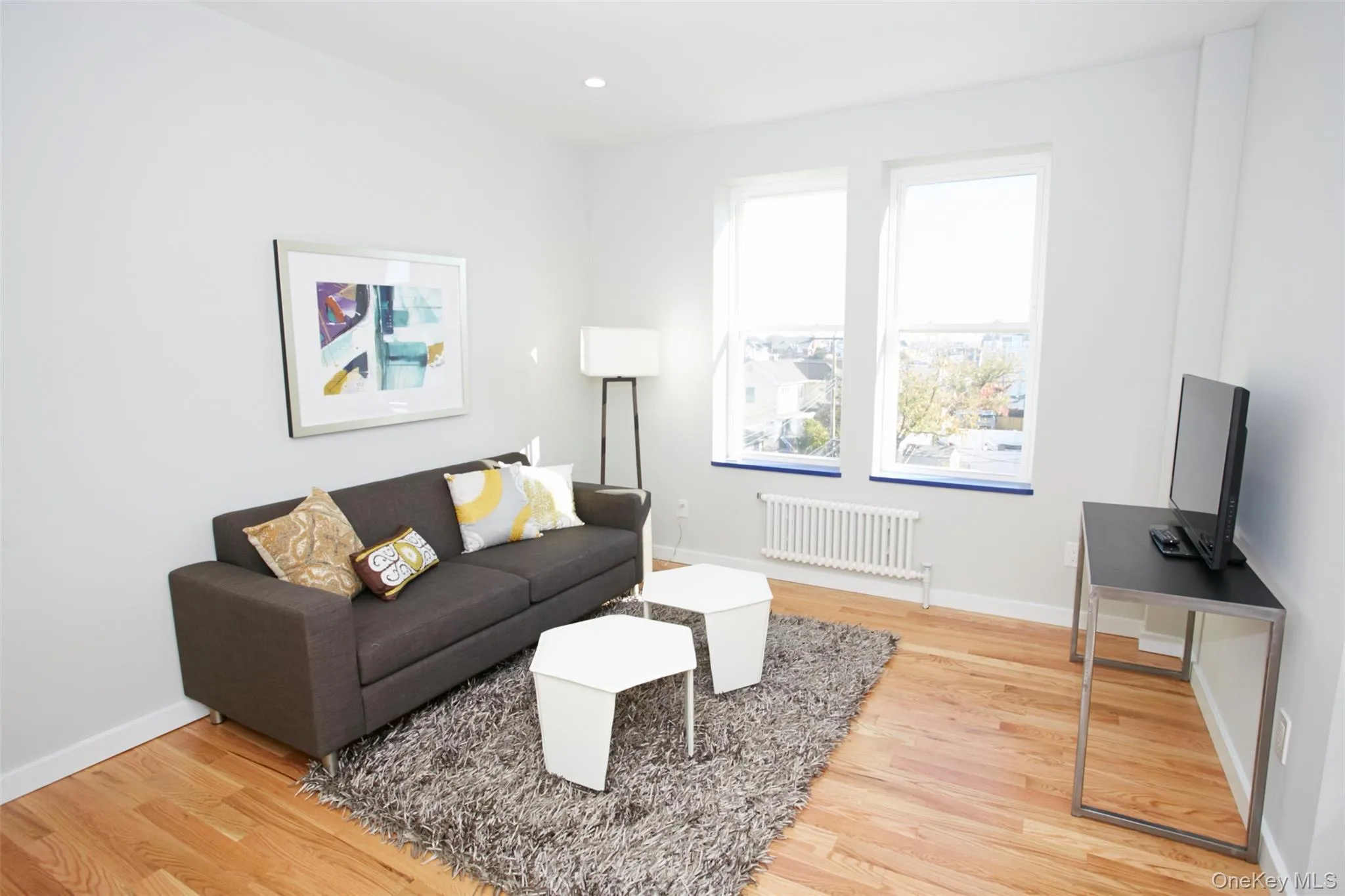 Living room with light wood-style flooring, radiator heating unit, and recessed lighting Living room with light wood-style flooring, radiator heating unit, and recessed lighting