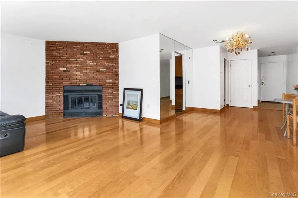 Unfurnished living room with a notable chandelier, light hardwood / wood-style flooring, and a fireplace Unfurnished living room with a notable chandelier, light hardwood / wood-style flooring, and a fireplace