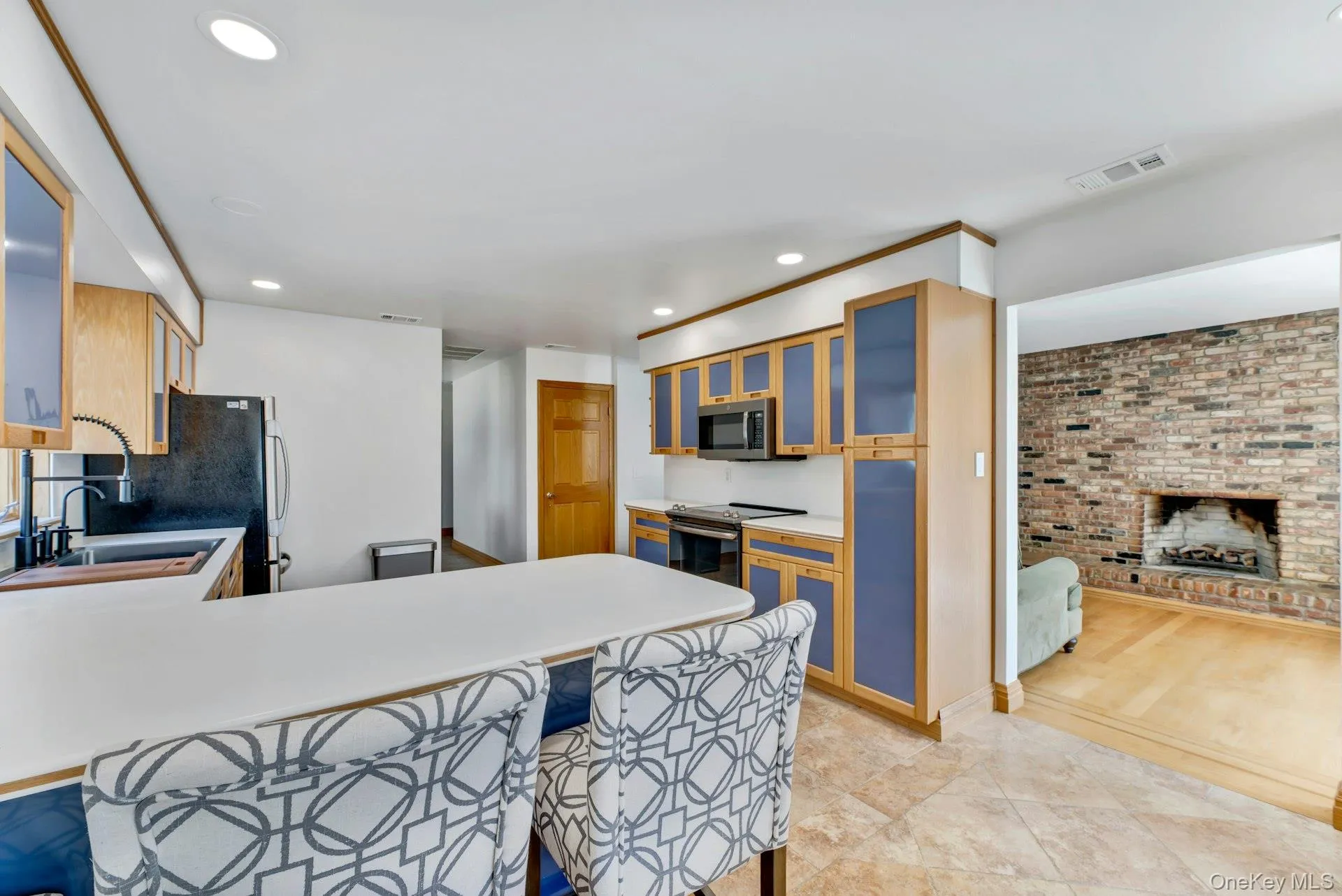 Kitchen with visible vents, a breakfast bar area, appliances with stainless steel finishes, a fireplace, and a sink Kitchen with visible vents, a breakfast bar area, appliances with stainless steel finishes, a fireplace, and a sink