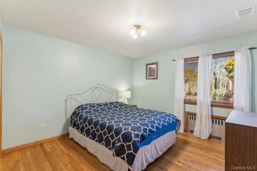 Bedroom featuring radiator and light wood-type flooring Bedroom featuring radiator and light wood-type flooring