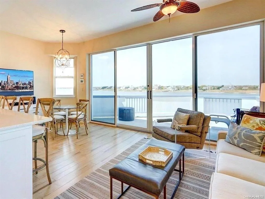 Living room featuring a water view, ceiling fan with notable chandelier, and light hardwood / wood-style floors Living room featuring a water view, ceiling fan with notable chandelier, and light hardwood / wood-style floors