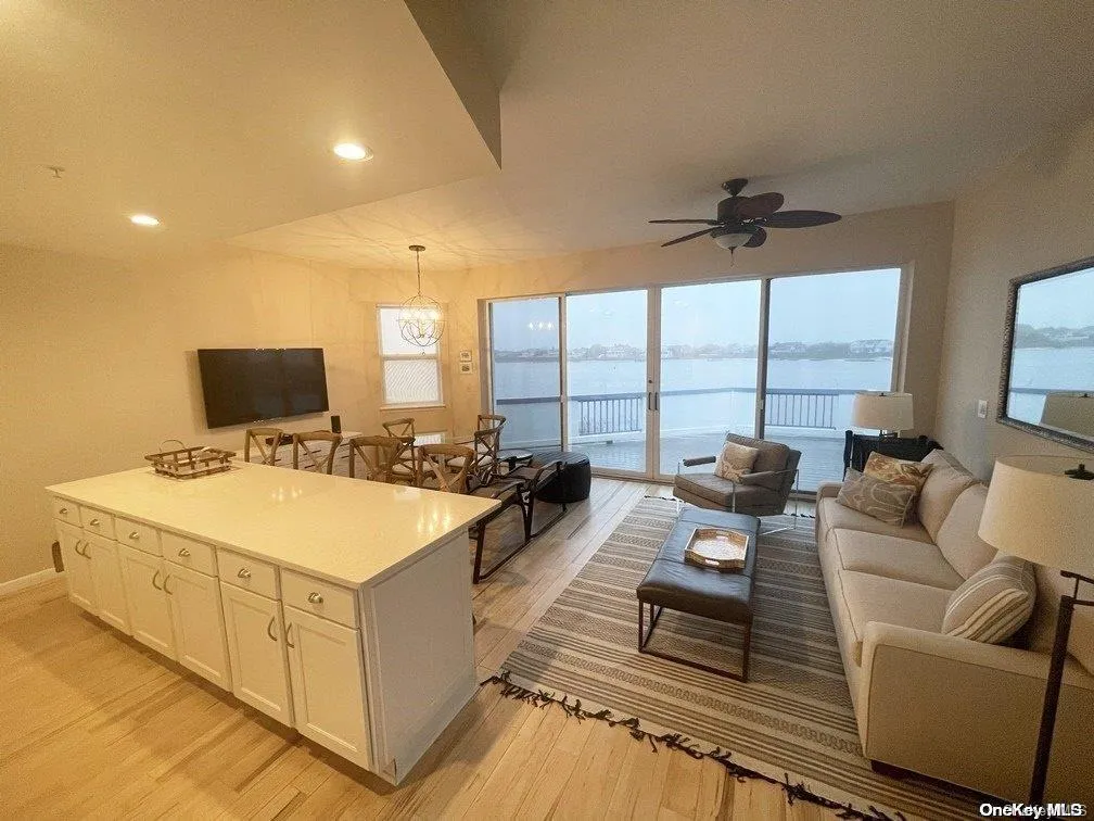 Kitchen featuring decorative light fixtures, ceiling fan with notable chandelier, white cabinetry, and light hardwood / wood-style floors Kitchen featuring decorative light fixtures, ceiling fan with notable chandelier, white cabinetry, and light hardwood / wood-style floors