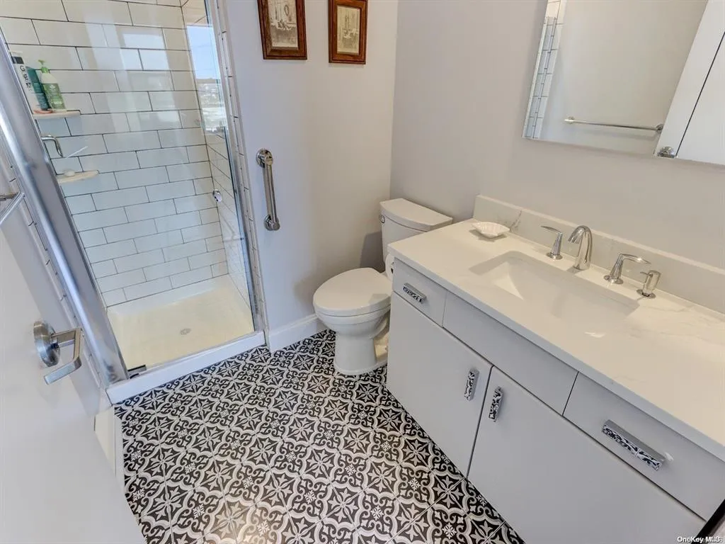 Bathroom featuring a shower with shower door, toilet, and vanity Bathroom featuring a shower with shower door, toilet, and vanity