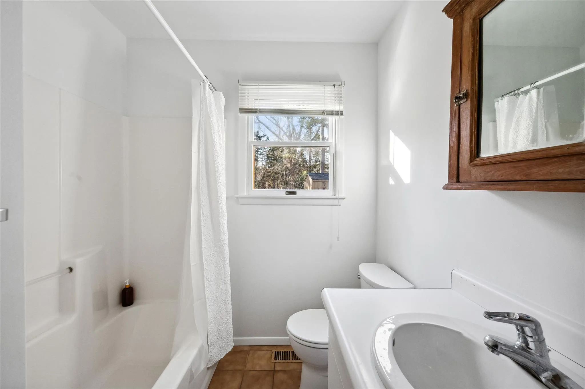 Full bathroom featuring toilet, vanity, tile patterned flooring, and shower / bath combination with curtain Full bathroom featuring toilet, vanity, tile patterned flooring, and shower / bath combination with curtain
