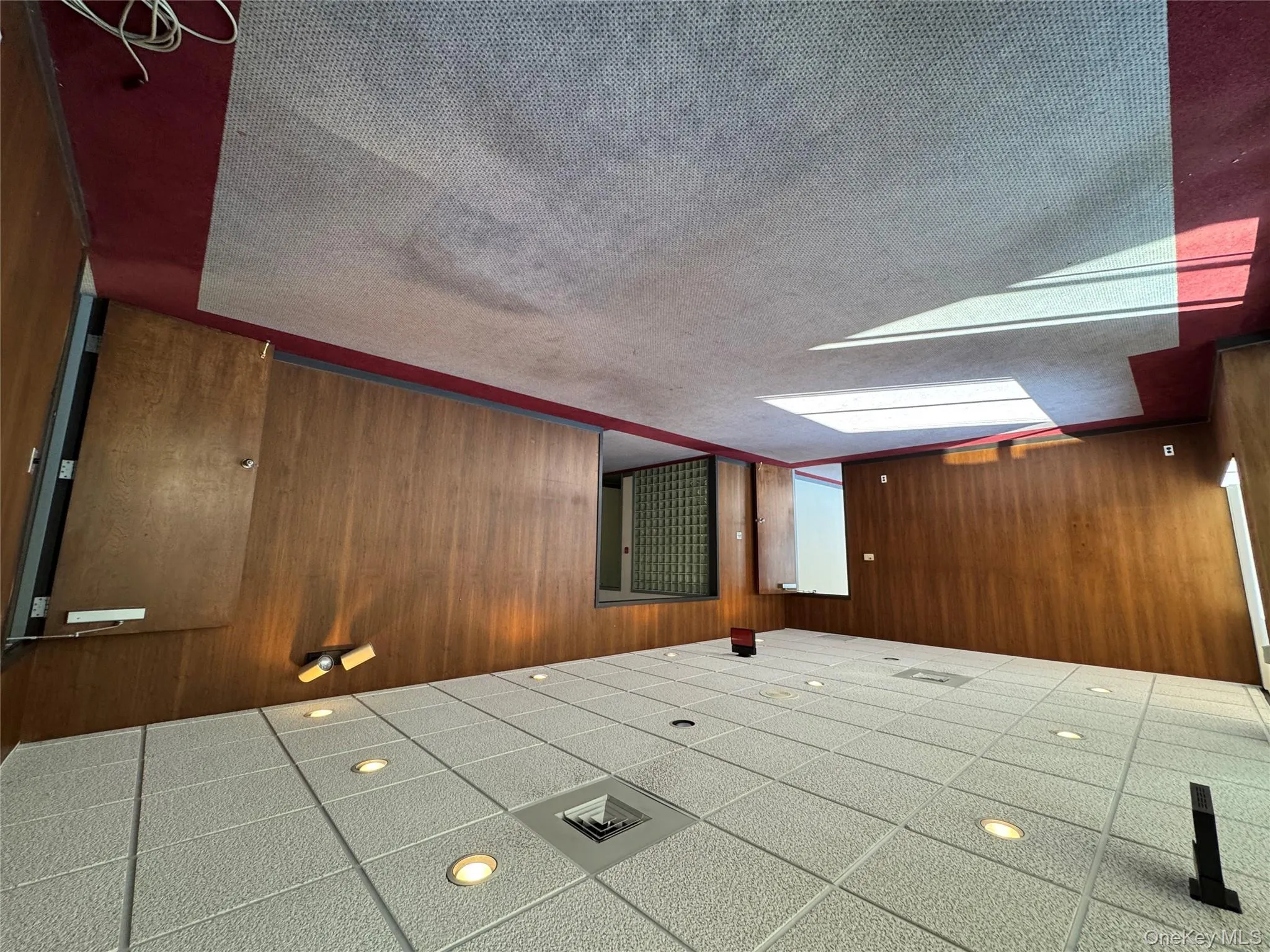 Unfurnished room featuring a drop ceiling, dark carpet, and wood walls Unfurnished room featuring a drop ceiling, dark carpet, and wood walls