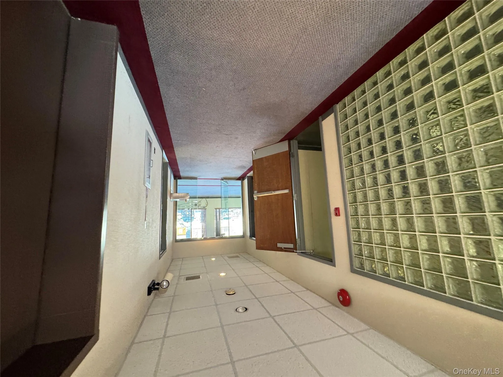 Hall featuring a paneled ceiling and dark carpet Hall featuring a paneled ceiling and dark carpet