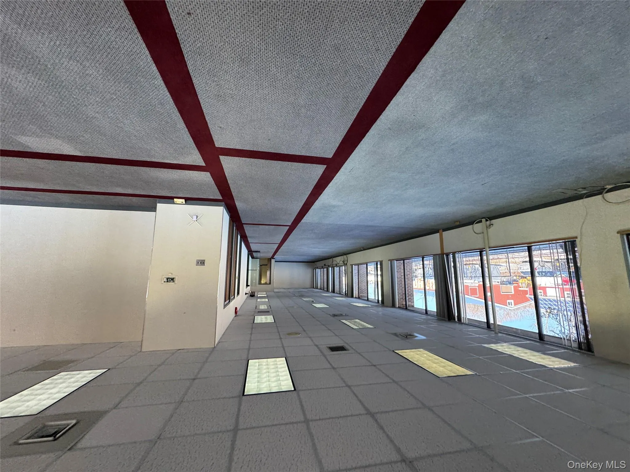 Empty room with a drop ceiling and dark carpet Empty room with a drop ceiling and dark carpet