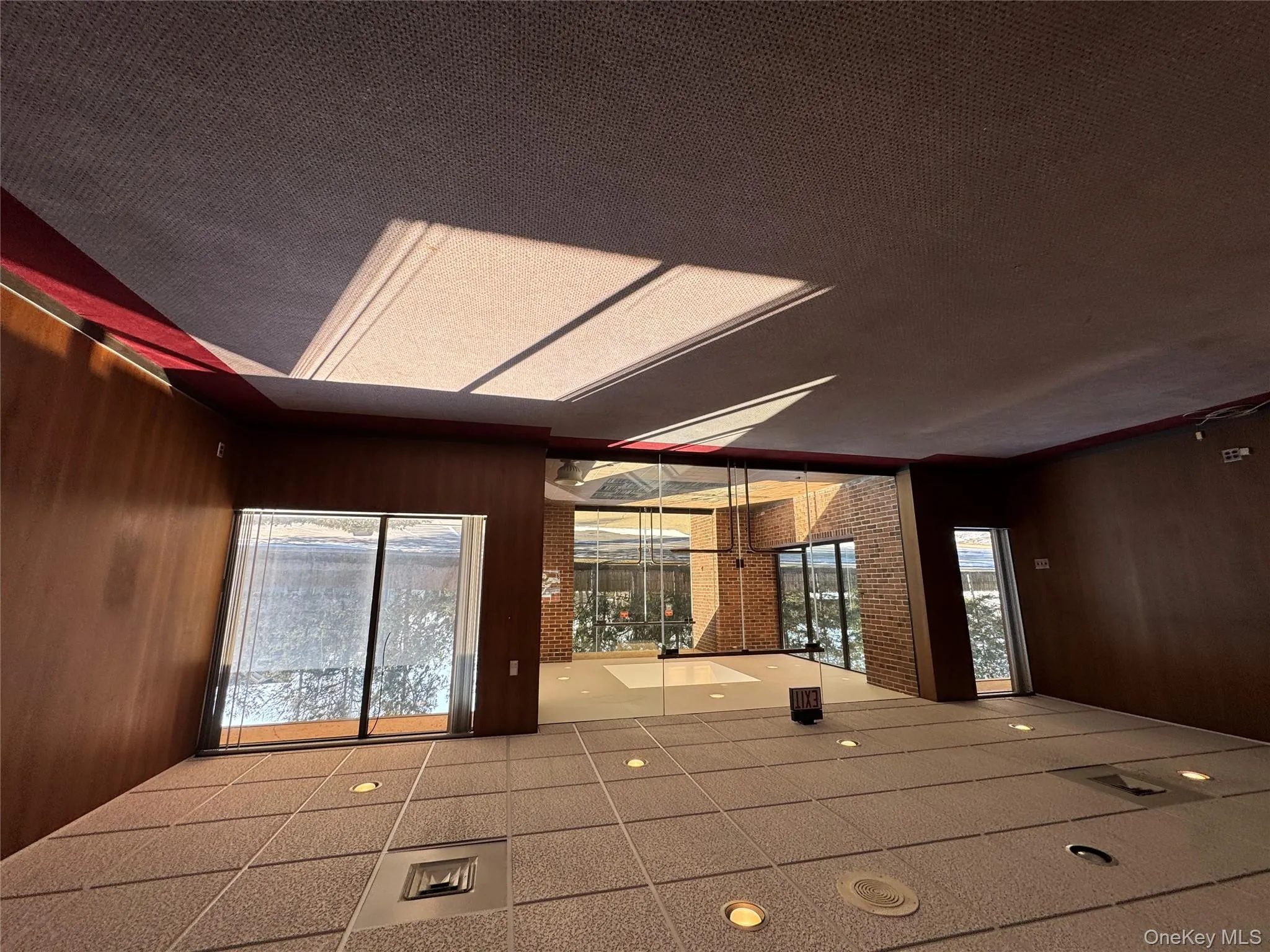 Unfurnished room featuring carpet floors, wooden walls, and a healthy amount of sunlight Unfurnished room featuring carpet floors, wooden walls, and a healthy amount of sunlight