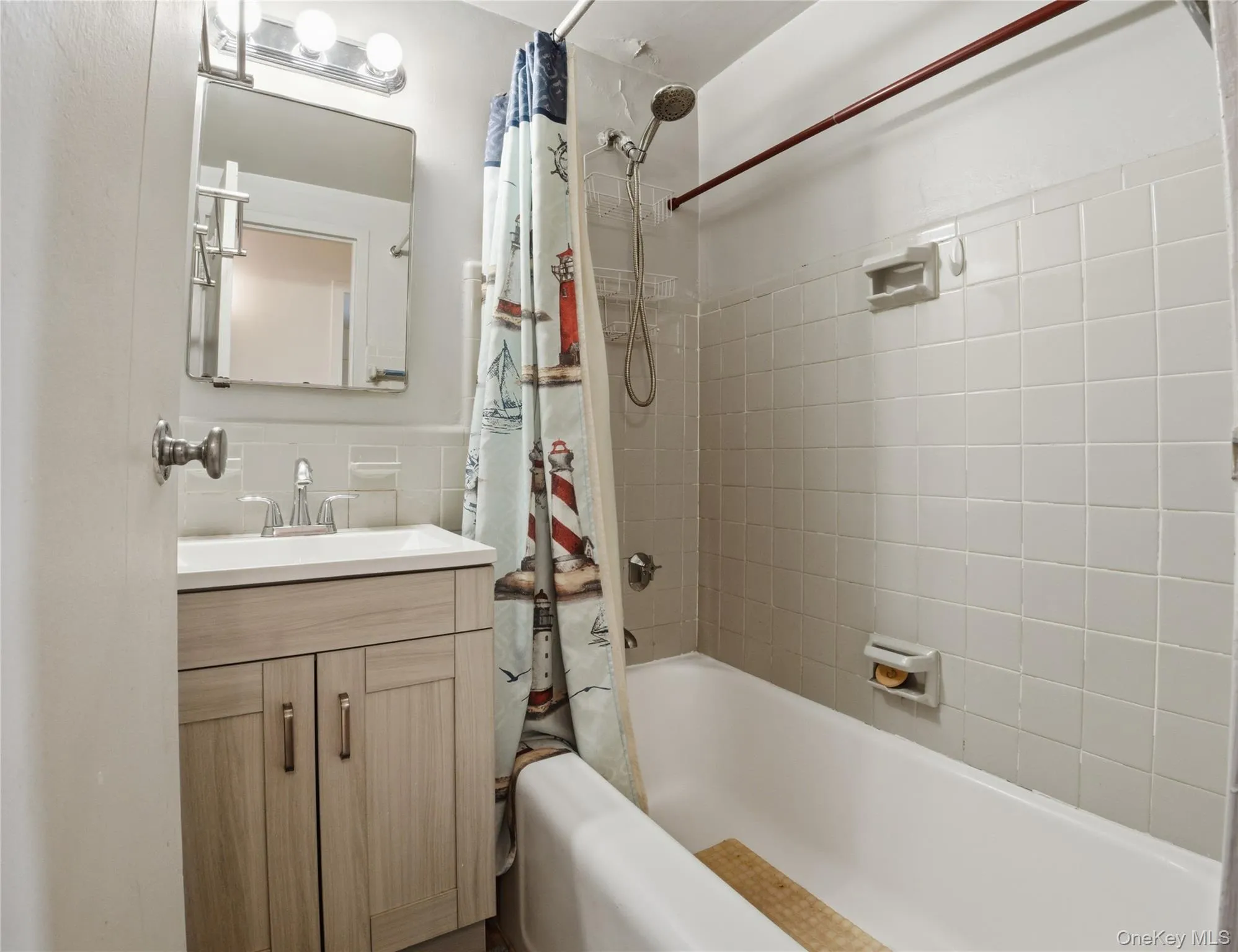 Full bathroom with shower / bath combo, vanity, and tile walls Full bathroom with shower / bath combo, vanity, and tile walls