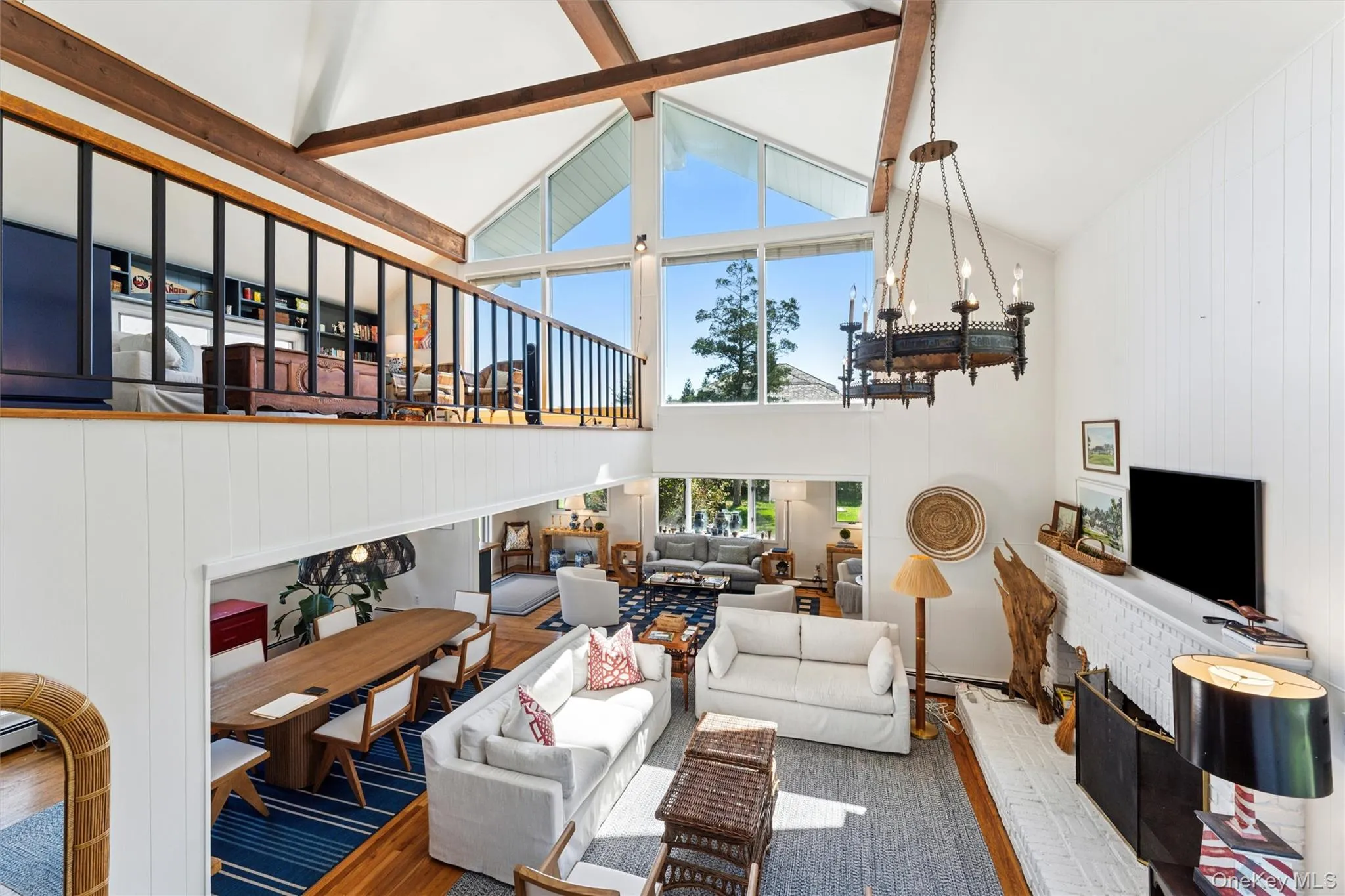 Living room featuring high vaulted ceiling, beam ceiling, wood finished floors, wooden walls, and a brick fireplace Living room featuring high vaulted ceiling, beam ceiling, wood finished floors, wooden walls, and a brick fireplace