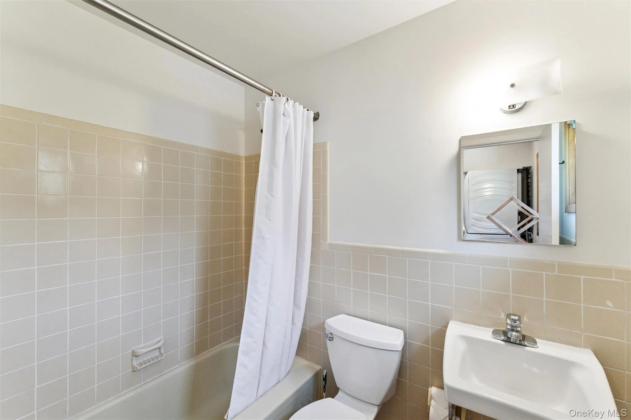 Full bathroom with shower / bathtub combination with curtain, tile walls, and wainscoting Full bathroom with shower / bathtub combination with curtain, tile walls, and wainscoting