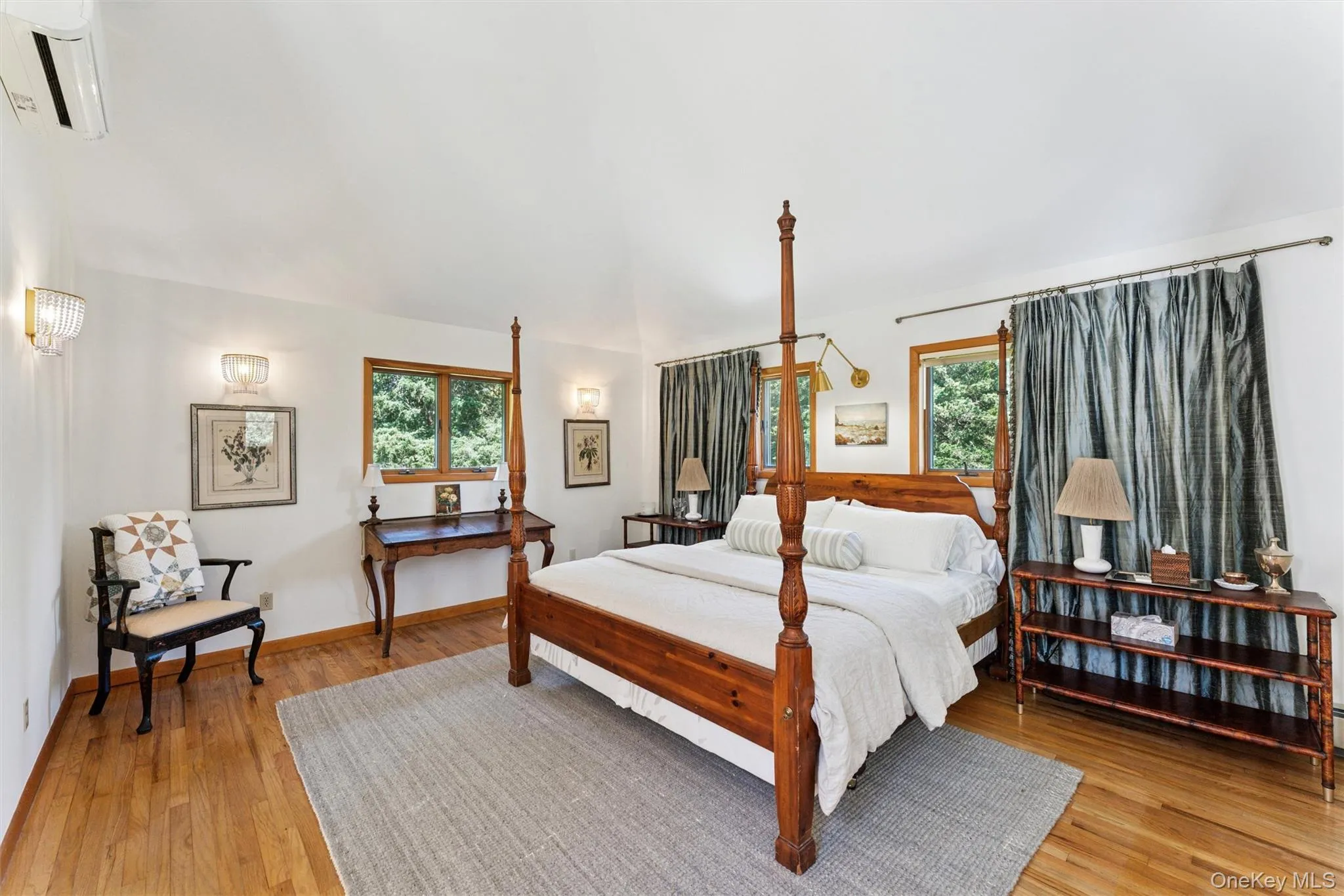 Bedroom featuring multiple windows, an AC wall unit, and light wood finished floors Bedroom featuring multiple windows, an AC wall unit, and light wood finished floors