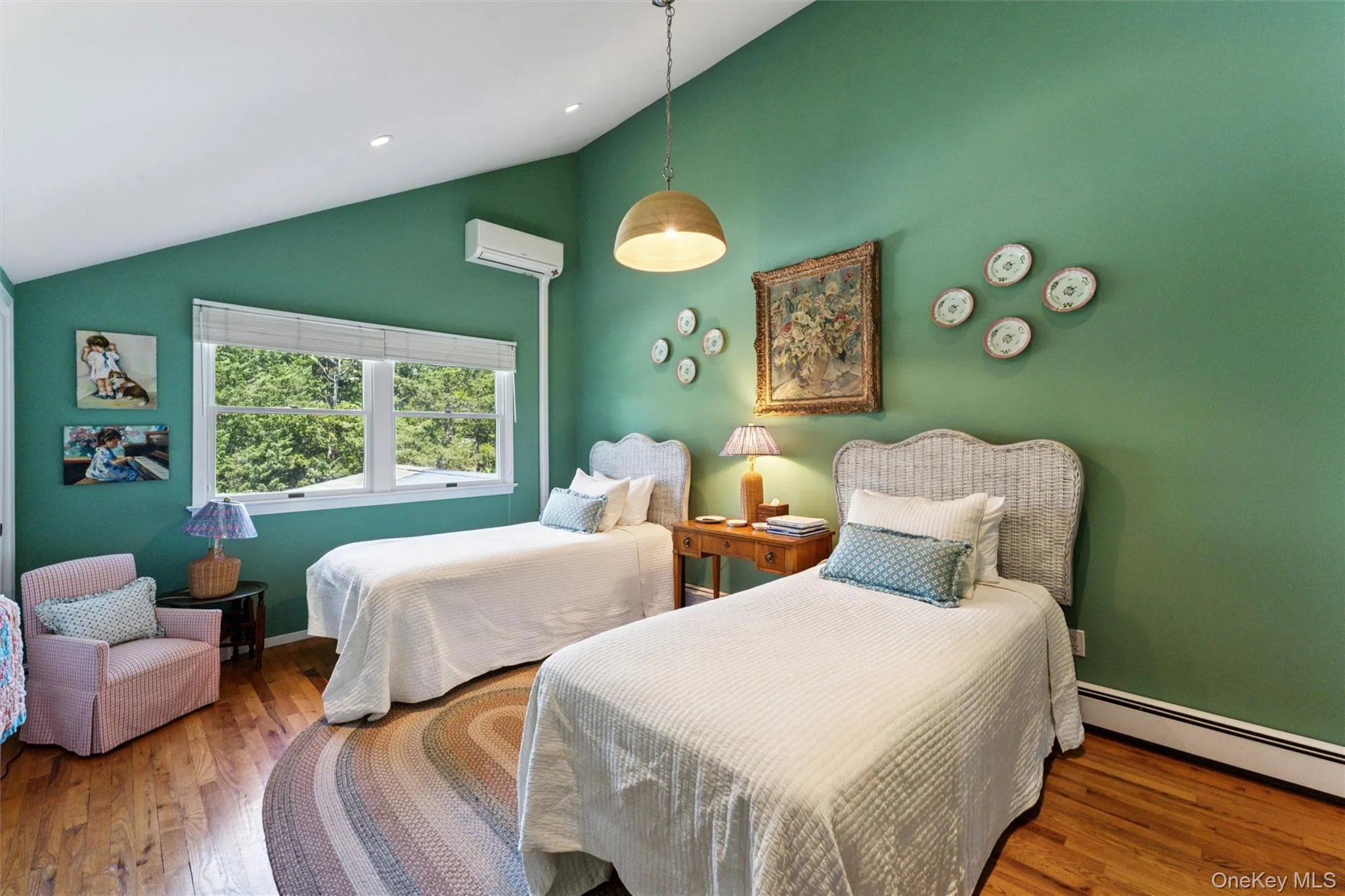 Bedroom featuring wood finished floors, baseboard heating, high vaulted ceiling, and a wall mounted air conditioner Bedroom featuring wood finished floors, baseboard heating, high vaulted ceiling, and a wall mounted air conditioner