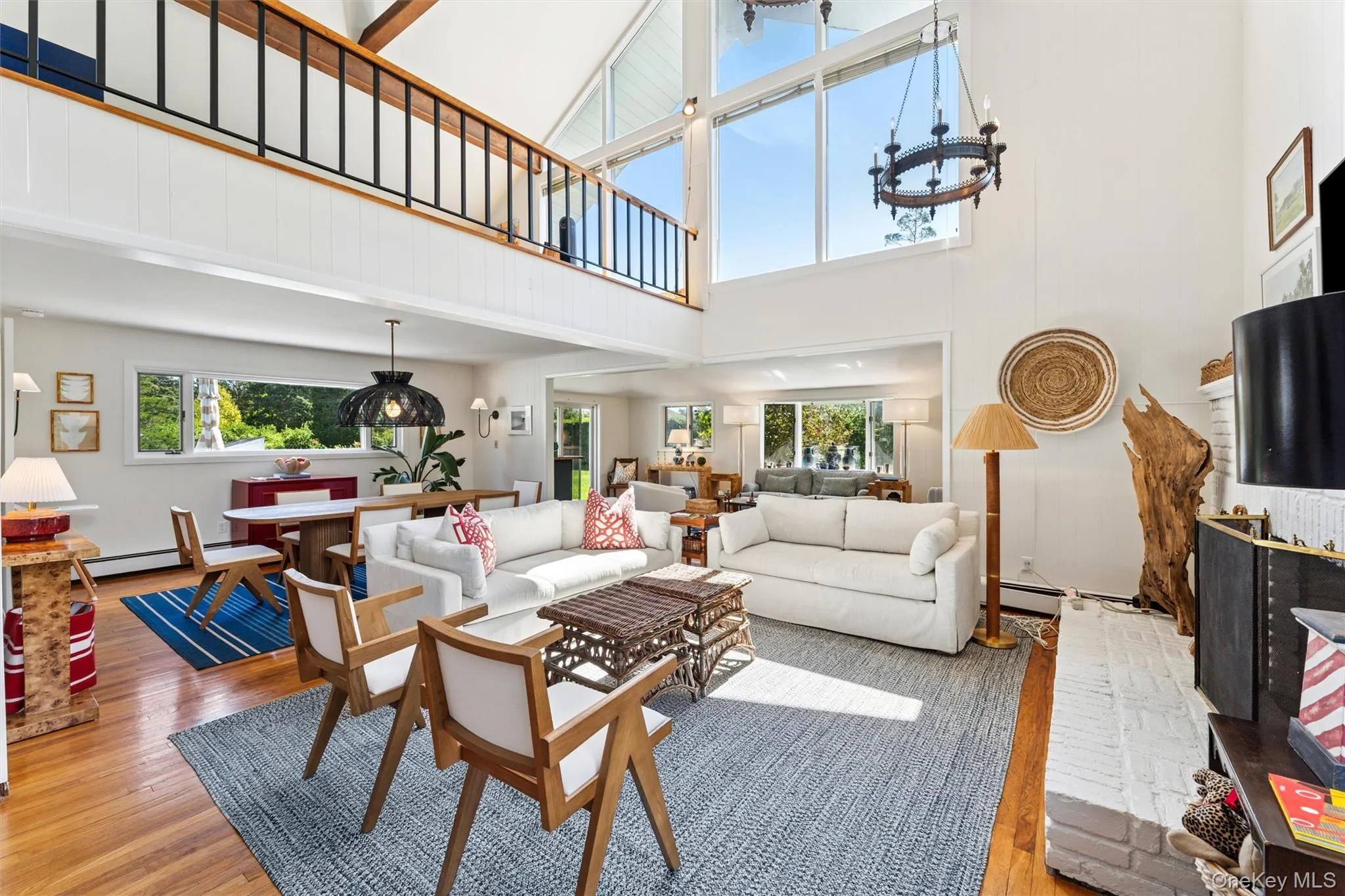 Living area with a towering ceiling, healthy amount of natural light, wood finished floors, and a chandelier Living area with a towering ceiling, healthy amount of natural light, wood finished floors, and a chandelier