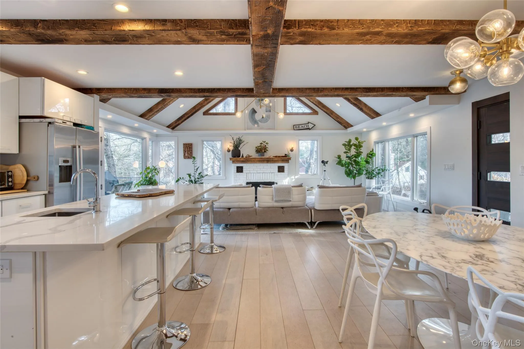 Kitchen with a breakfast bar, vaulted ceiling with beams, white cabinets, high quality fridge, and a sink Kitchen with a breakfast bar, vaulted ceiling with beams, white cabinets, high quality fridge, and a sink