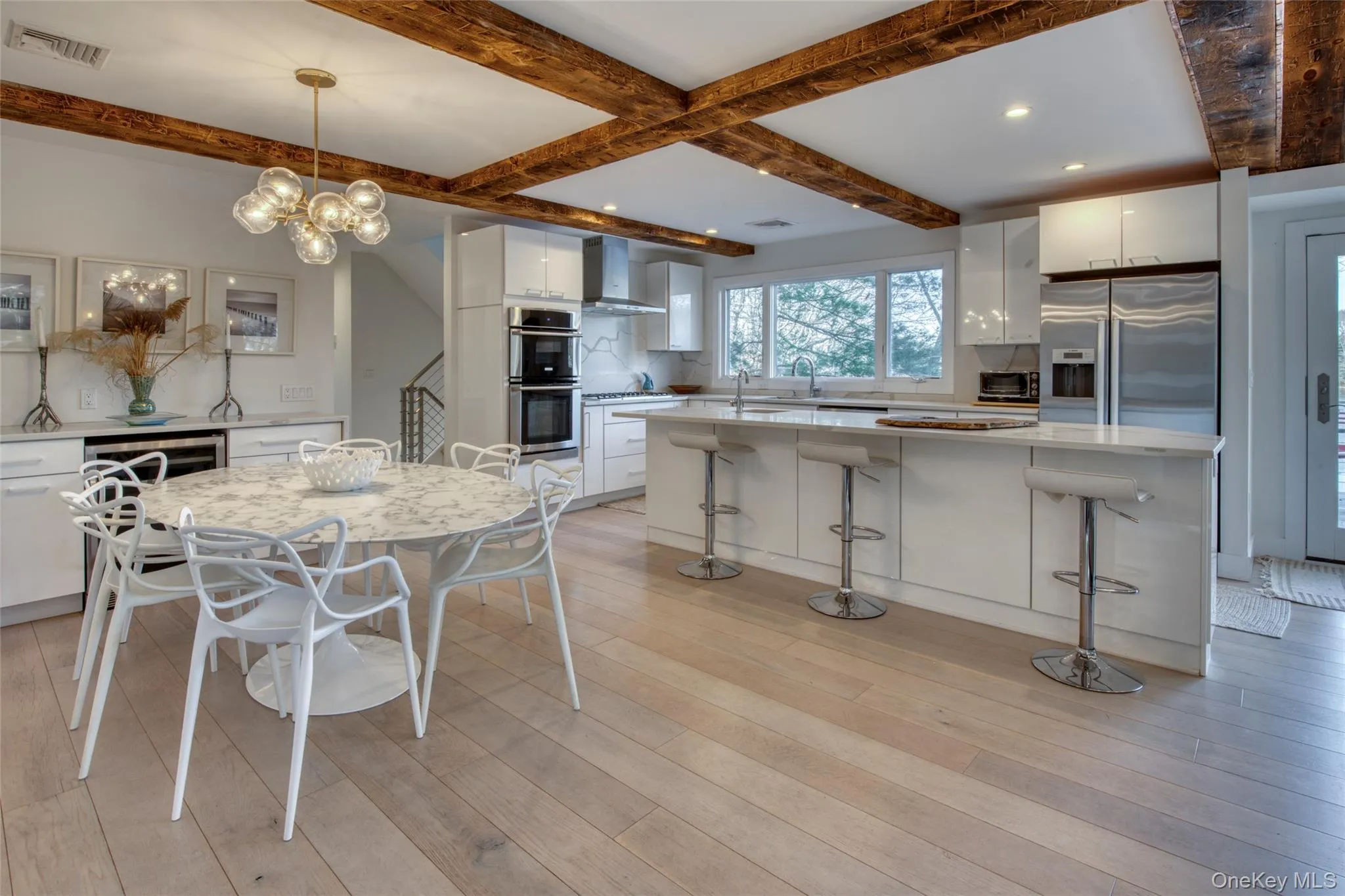 Kitchen with tasteful backsplash, wall chimney exhaust hood, white cabinetry, and stainless steel appliances Kitchen with tasteful backsplash, wall chimney exhaust hood, white cabinetry, and stainless steel appliances