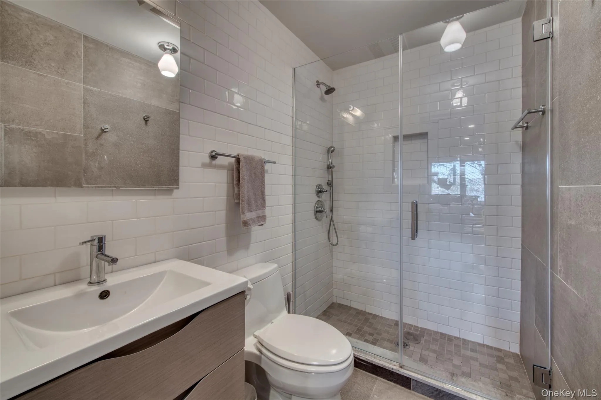 Full bathroom with toilet, vanity, tile walls, a shower stall, and tasteful backsplash Full bathroom with toilet, vanity, tile walls, a shower stall, and tasteful backsplash