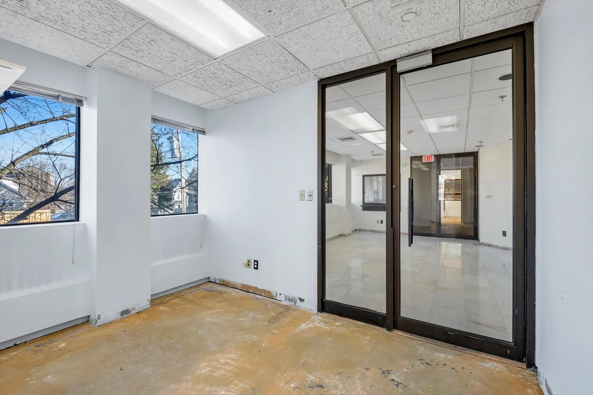 Empty room with a paneled ceiling and concrete flooring Empty room with a paneled ceiling and concrete flooring