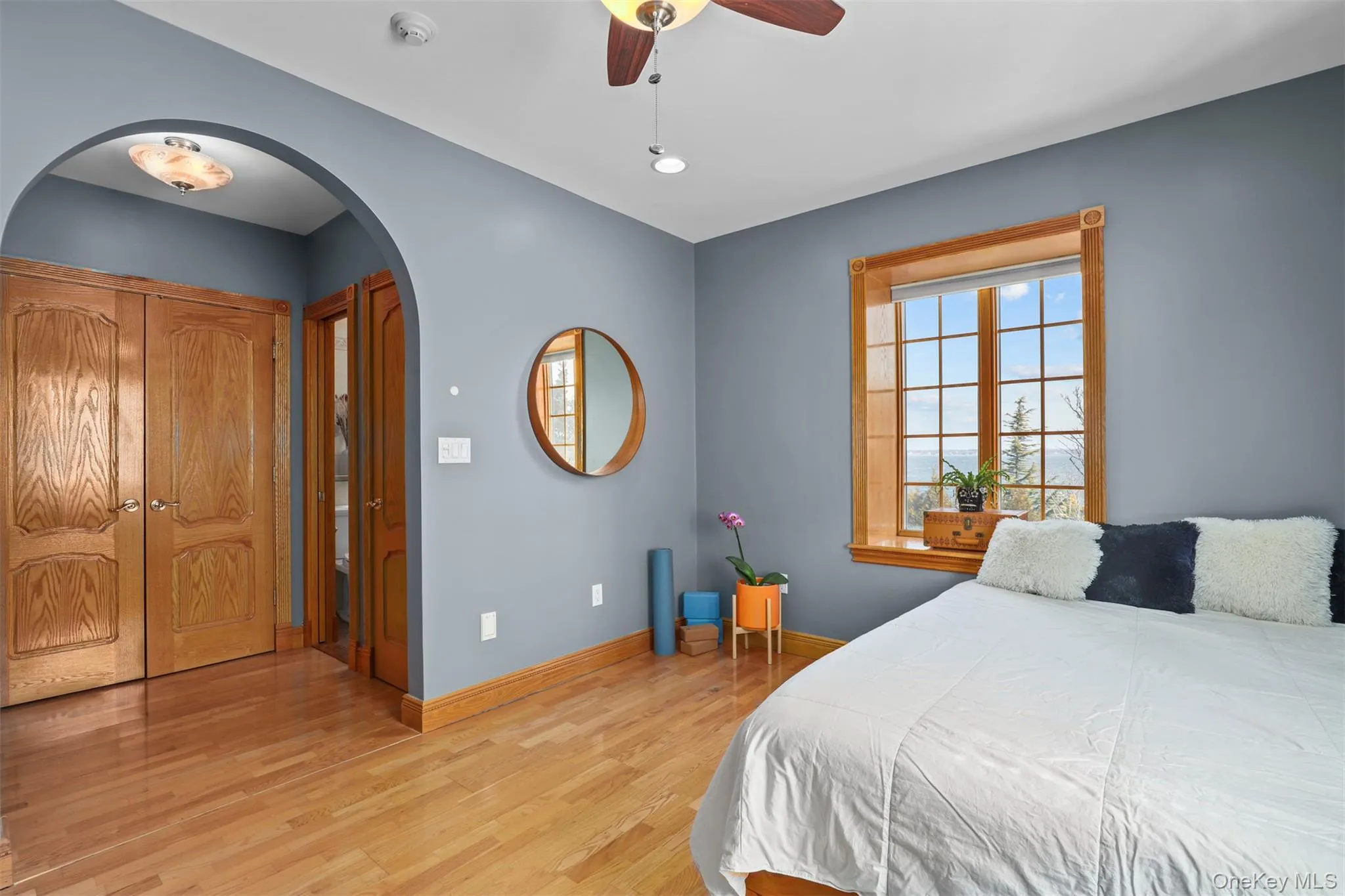 Bedroom featuring arched walkways, light wood-style flooring, baseboards, and ceiling fan Bedroom featuring arched walkways, light wood-style flooring, baseboards, and ceiling fan