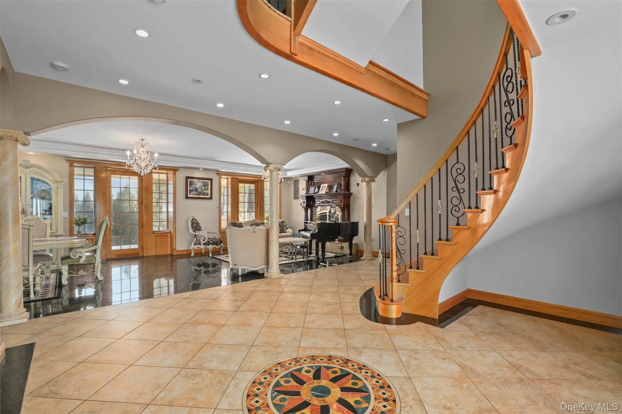 Foyer entrance with ornamental molding, arched walkways, decorative columns, baseboards, and a chandelier Foyer entrance with ornamental molding, arched walkways, decorative columns, baseboards, and a chandelier