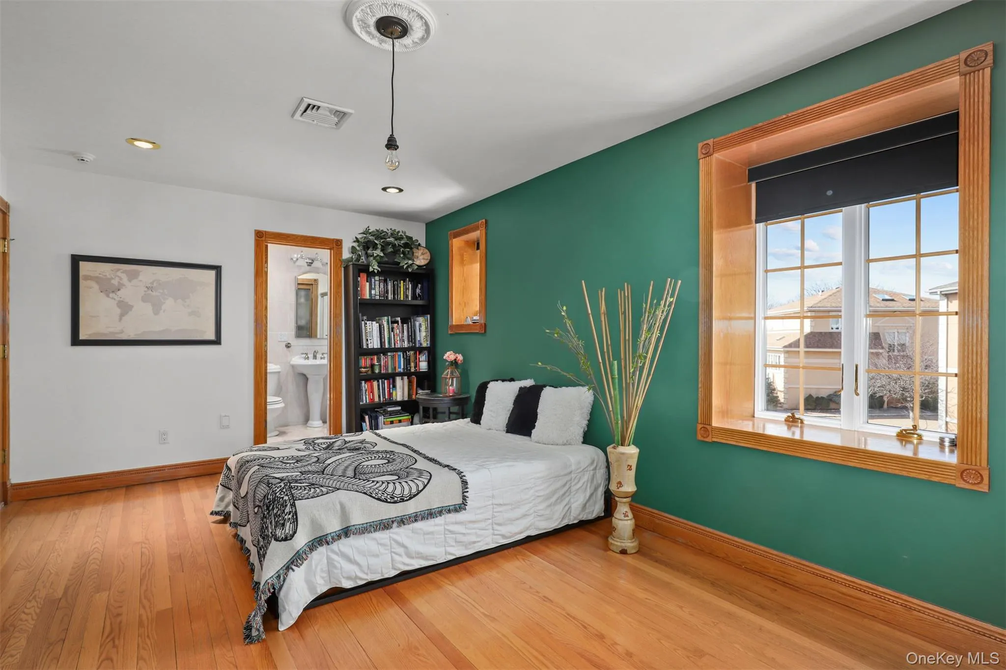Bedroom with connected bathroom, visible vents, baseboards, and wood finished floors Bedroom with connected bathroom, visible vents, baseboards, and wood finished floors