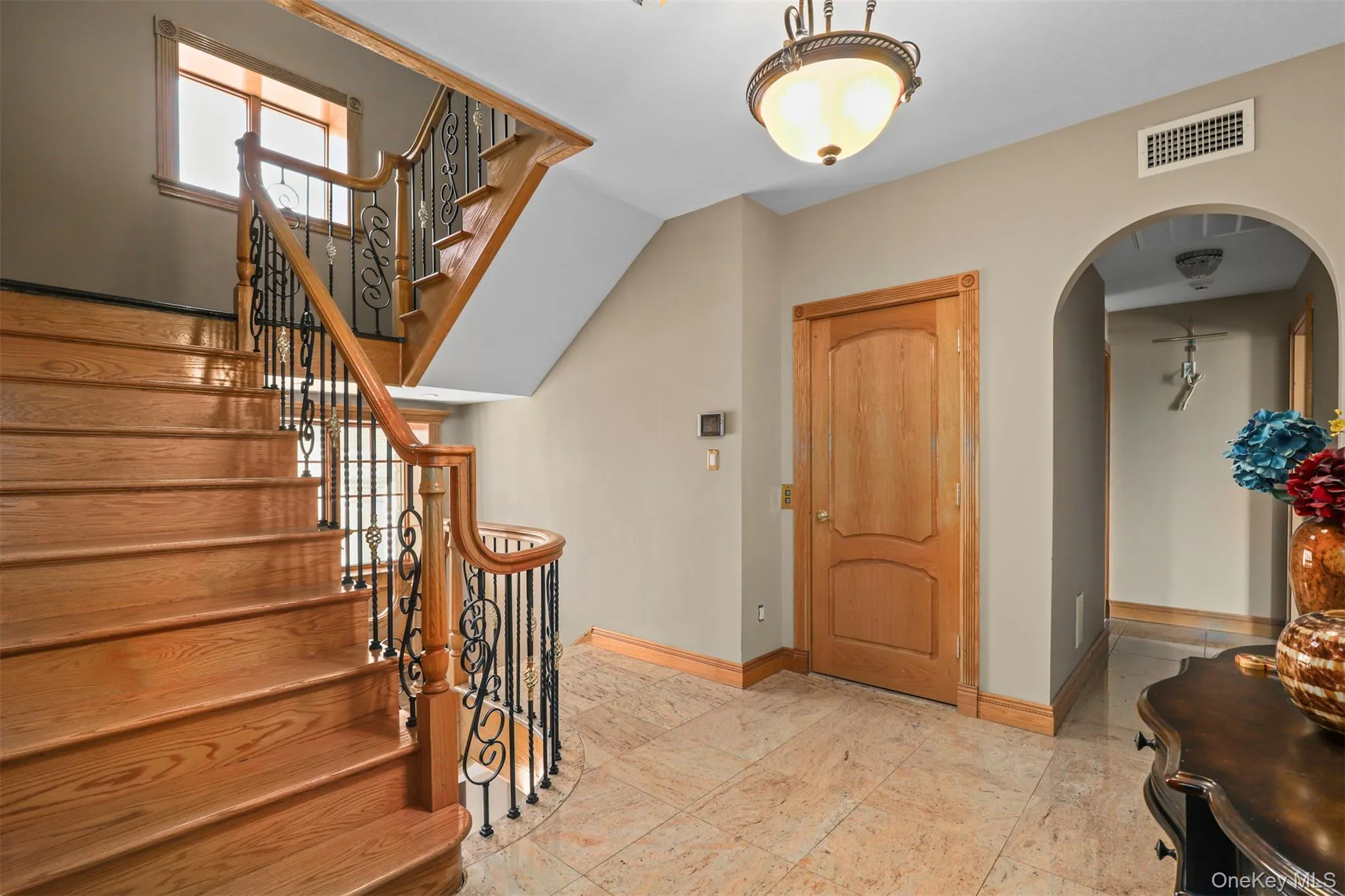 Entryway with arched walkways, visible vents, stairway, and baseboards Entryway with arched walkways, visible vents, stairway, and baseboards